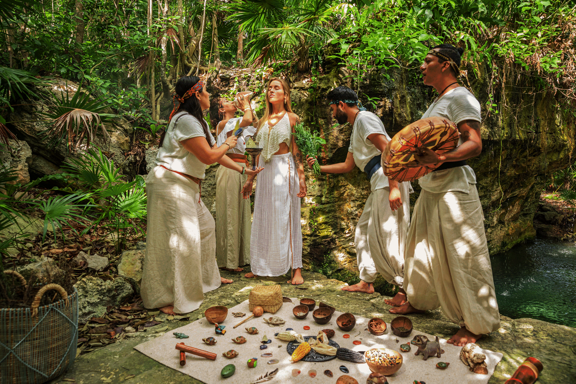 Small group gathered in a lush jungle clearing performing a traditional ritual with natural offerings arranged on the ground.