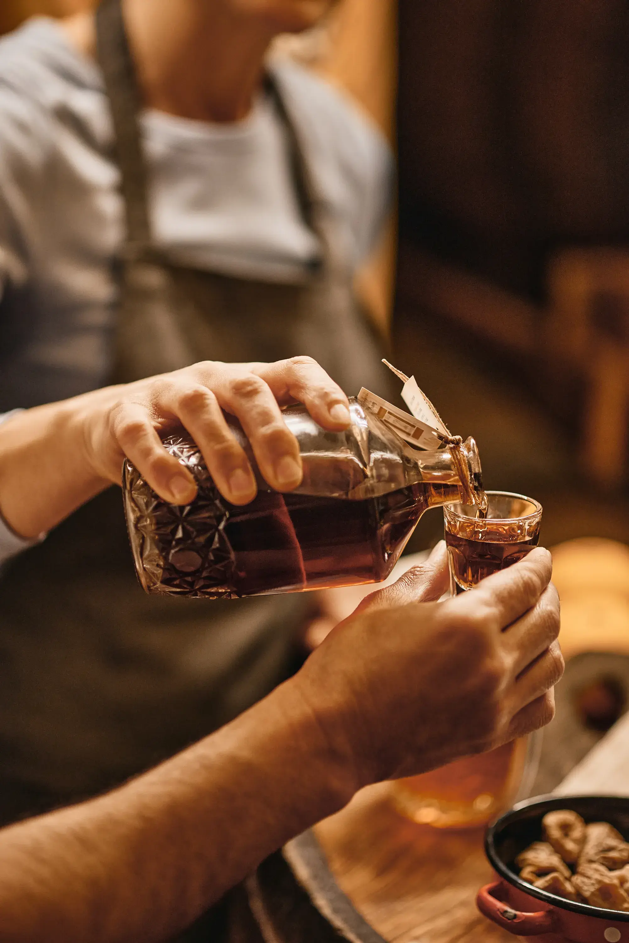 Close up of hands pouring a drink into a small shot glass 