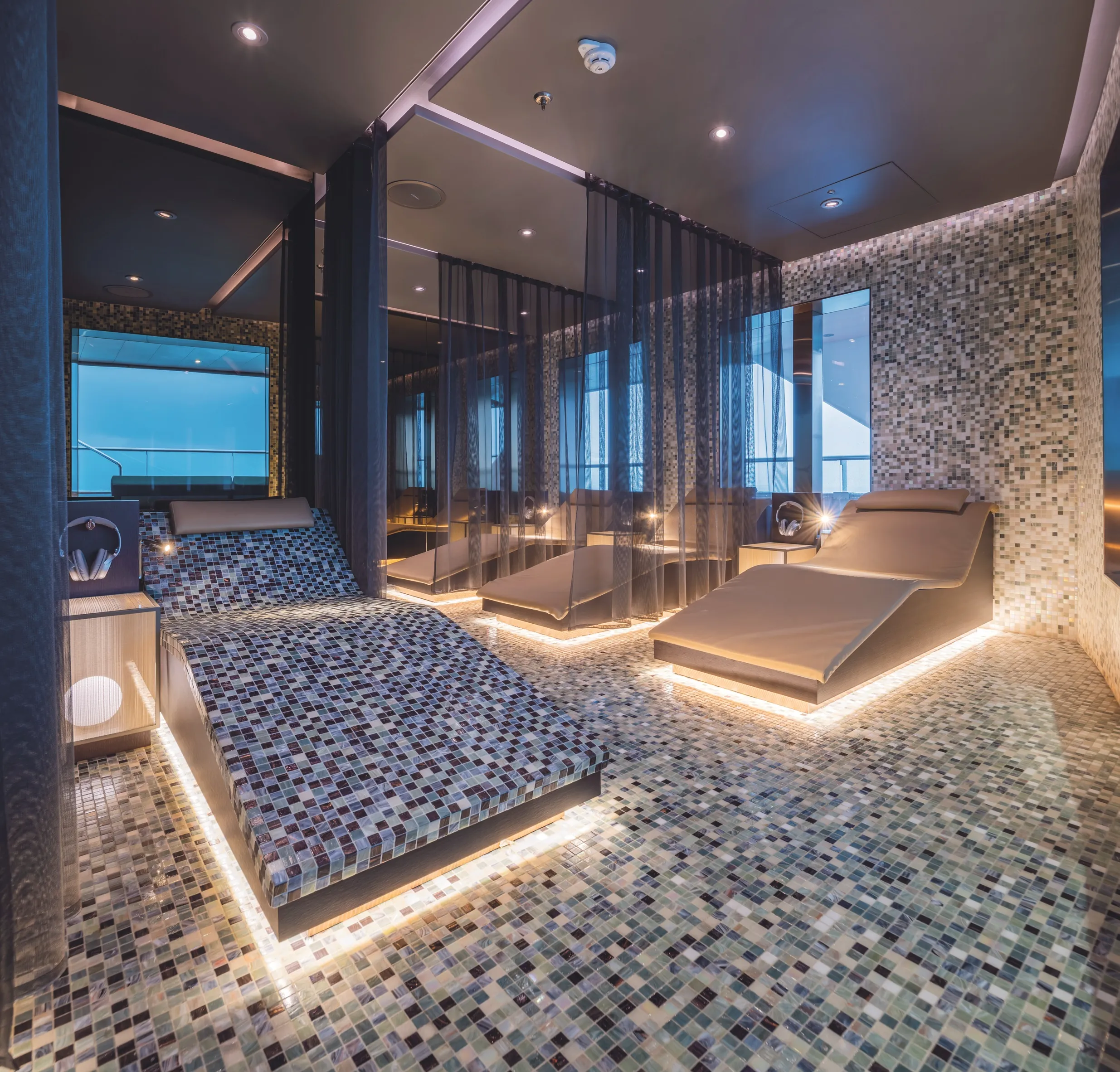 Luxurious spa room with mosaic tiles, reclining lounge chairs, and soft ambient lighting.