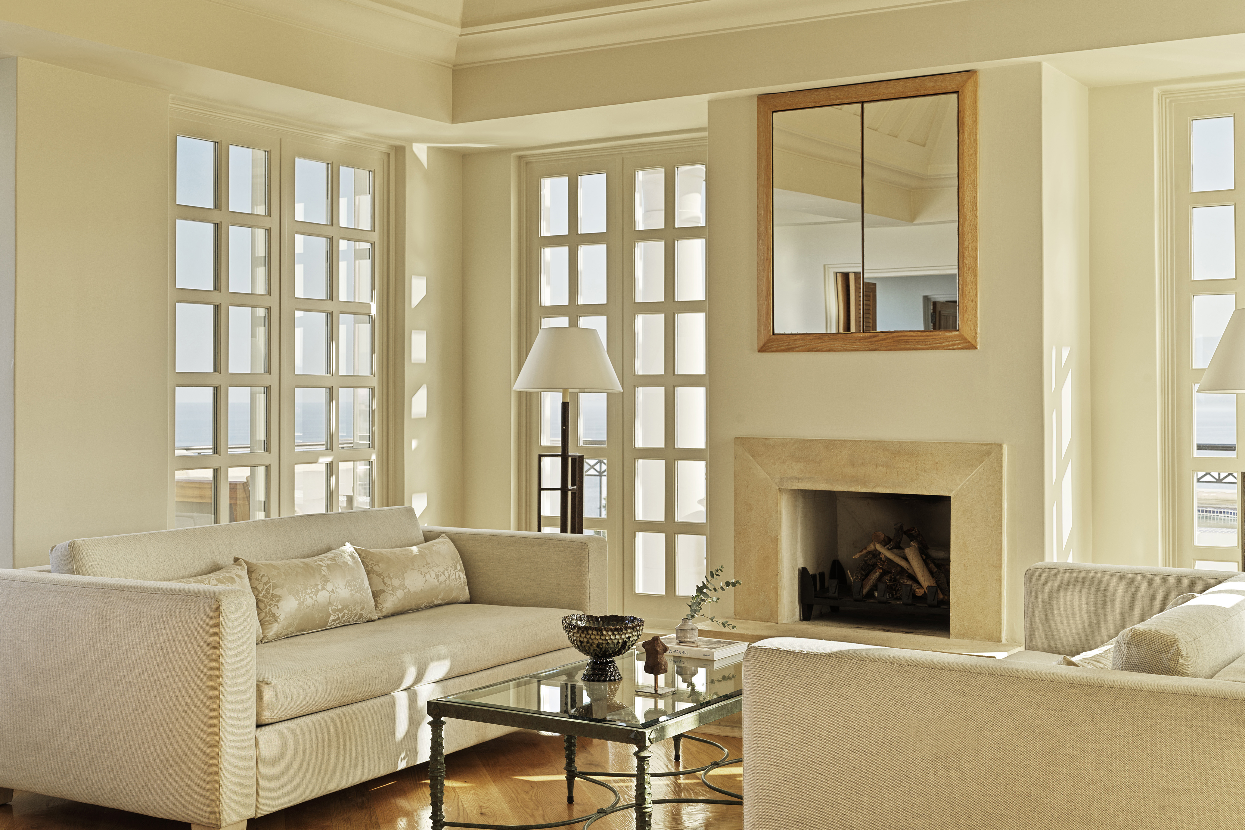 Lounge of Aphrodite Suite at Anassa in Cyprus featuring pale walls with glass doors surrounding pale sofas and sleek decor