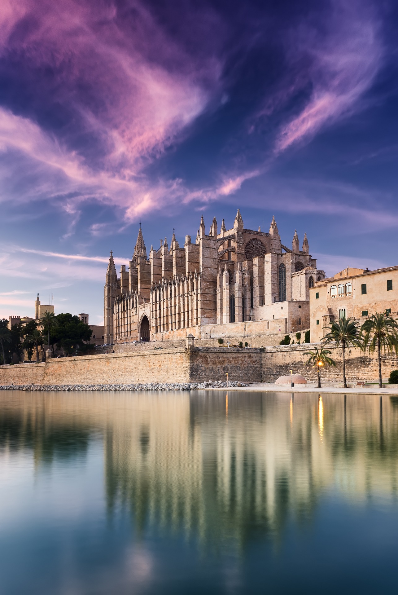 A stunning view of Palma's ornate cathedral as it reflects in the waters below on a blue sky day