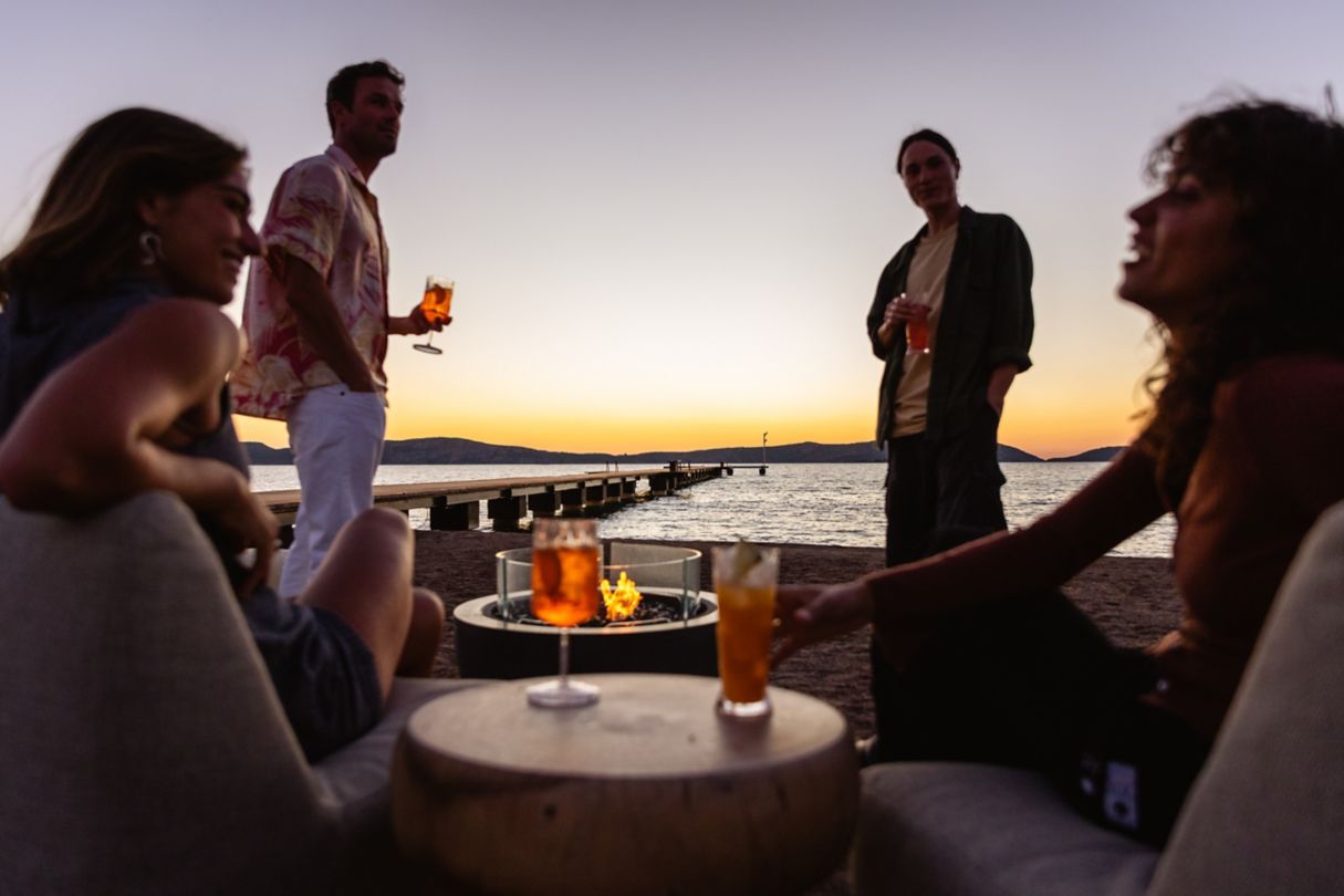 A group of people enjoying drinks around a bonfire