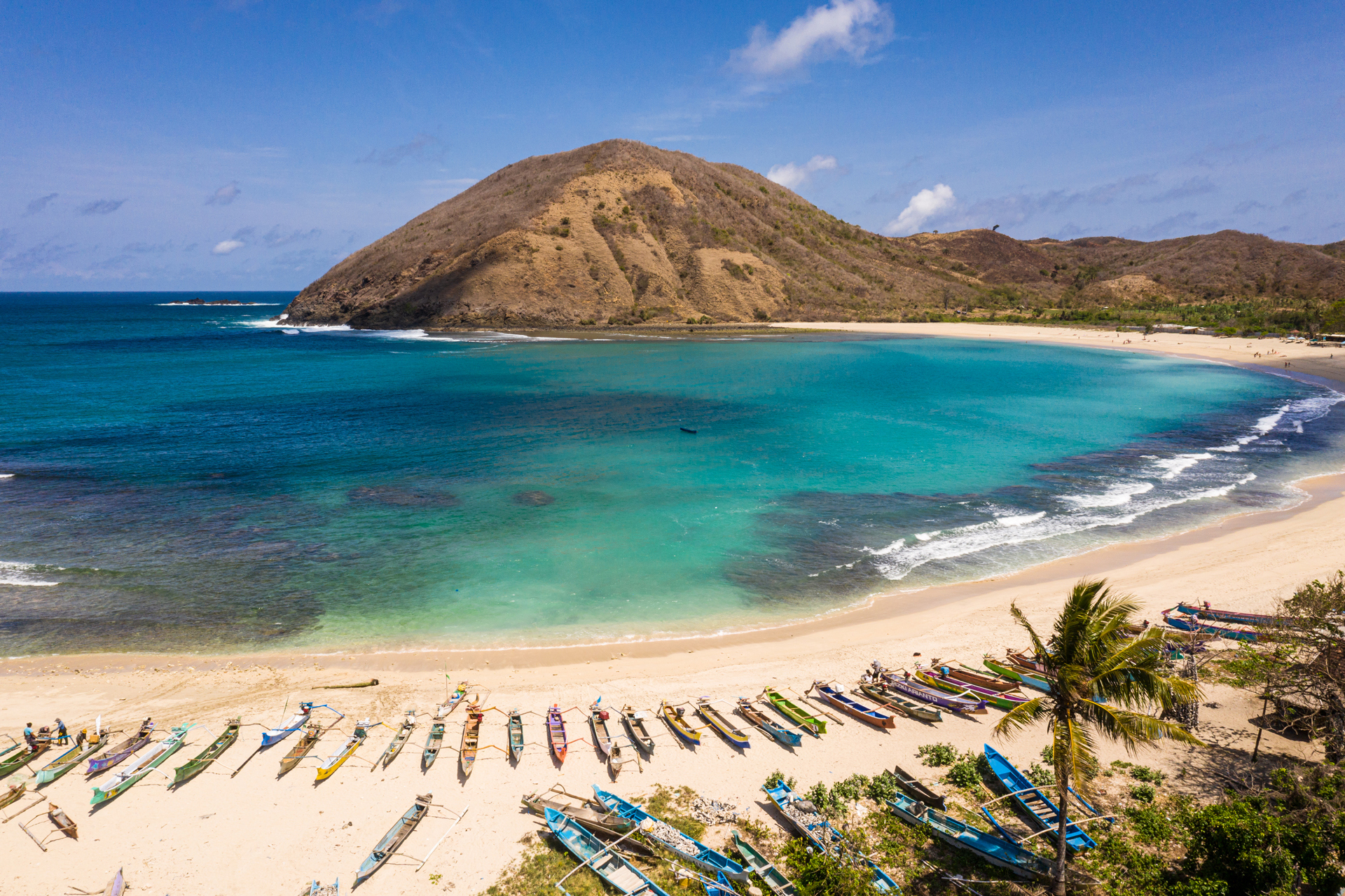 A beach with small boats and a mountain in the background