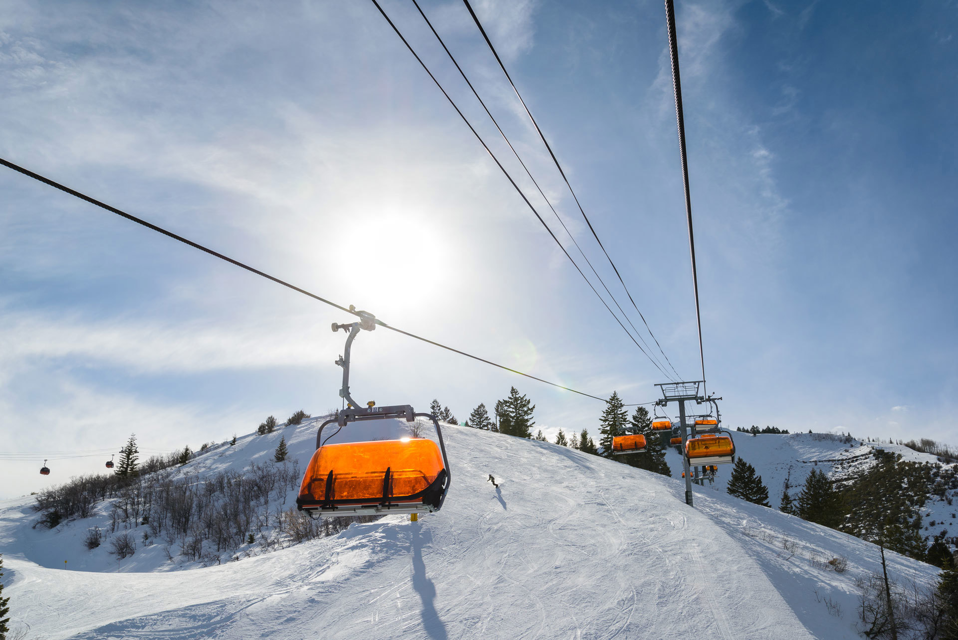 Riding a chairlift as a snowboarder passes below