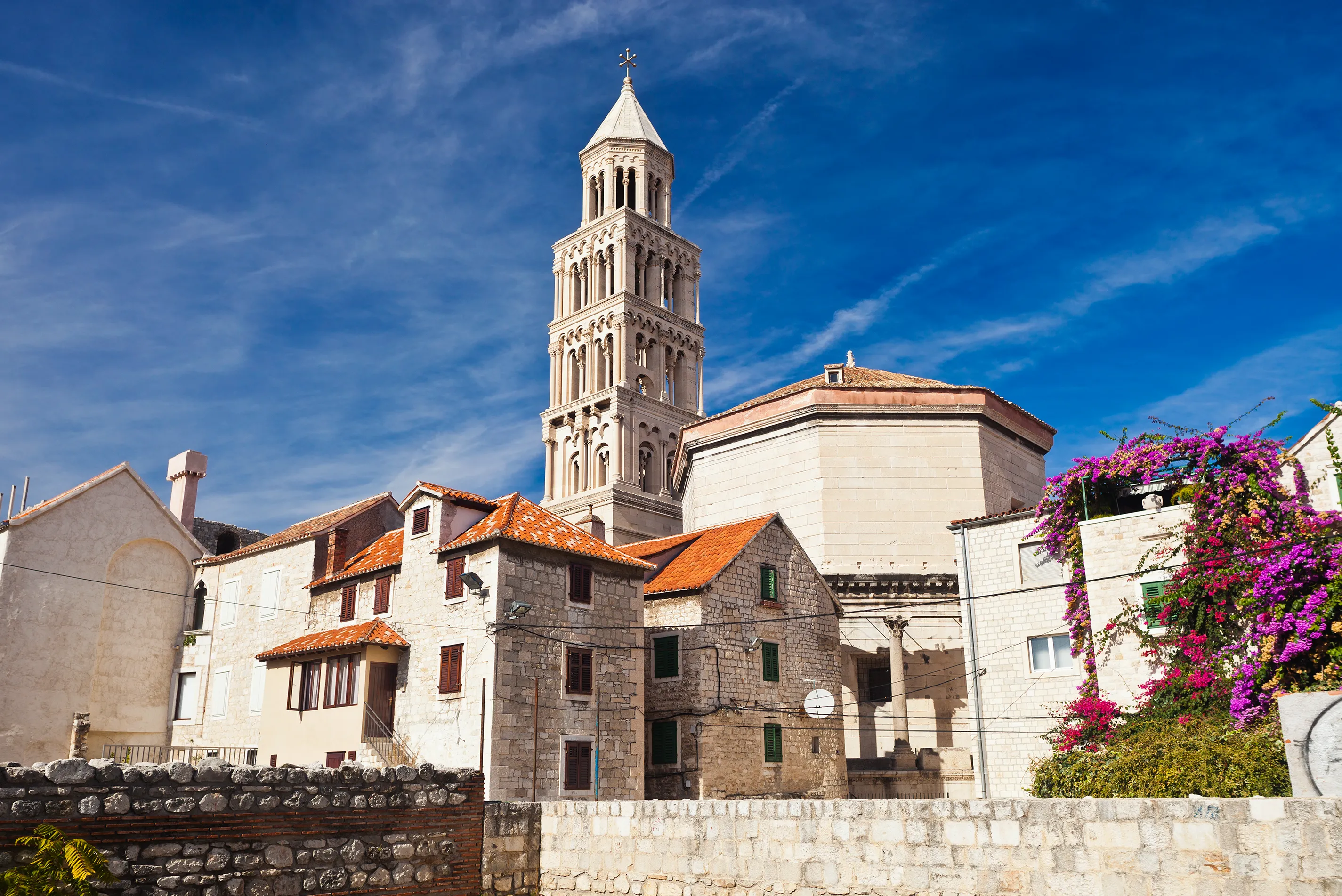 An ornate stone tower in Split standing above terracotta roofed buildings under a clear sky