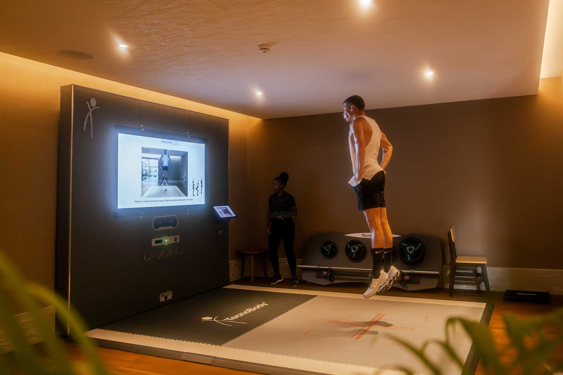 Personal training session at JOALI BEING using a digital fitness system in a modern indoor gym.