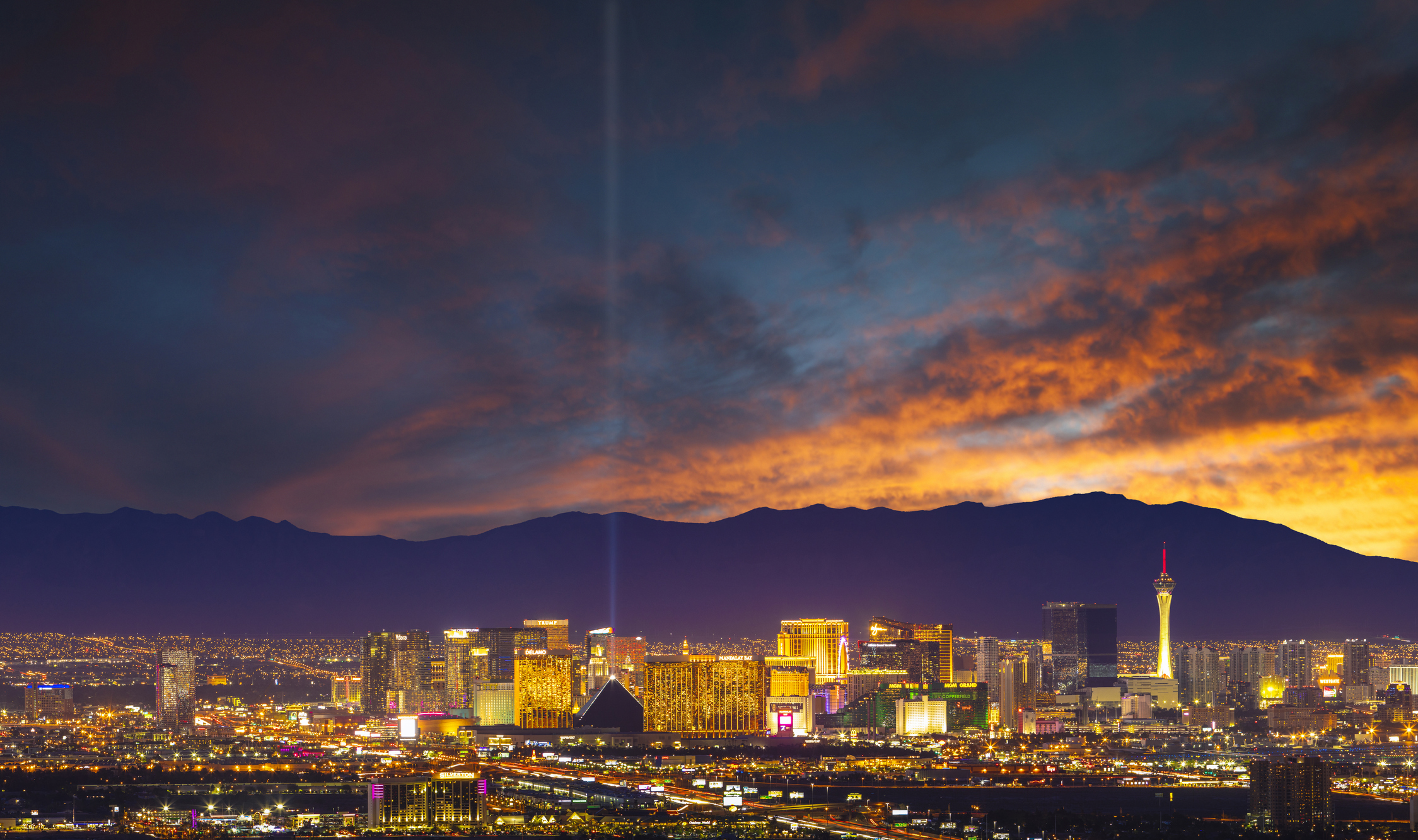 A view of the lit up Las Vegas city skyline with Nevada's mountains seen in the background