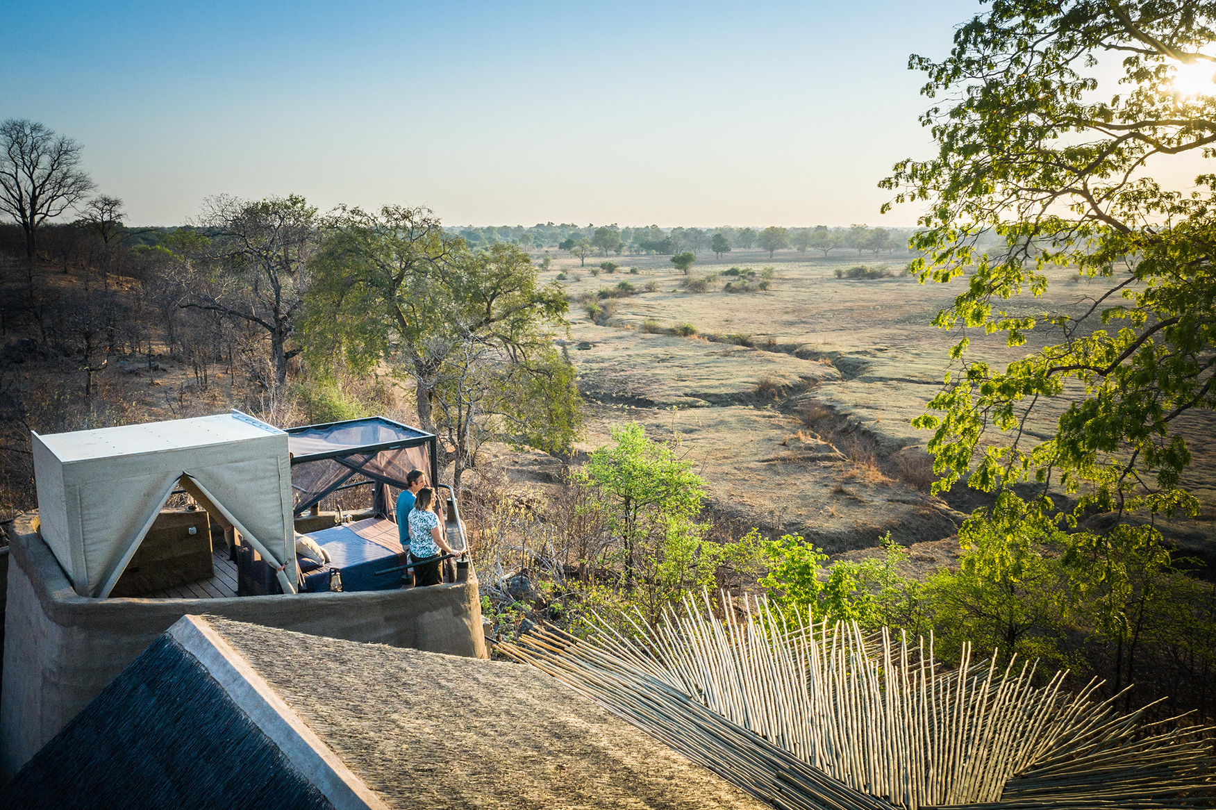 Africa, Zambia, South Luangwa National Park, Puku Ridge Camp, couple on private star beds tarrace looking out over the landscape