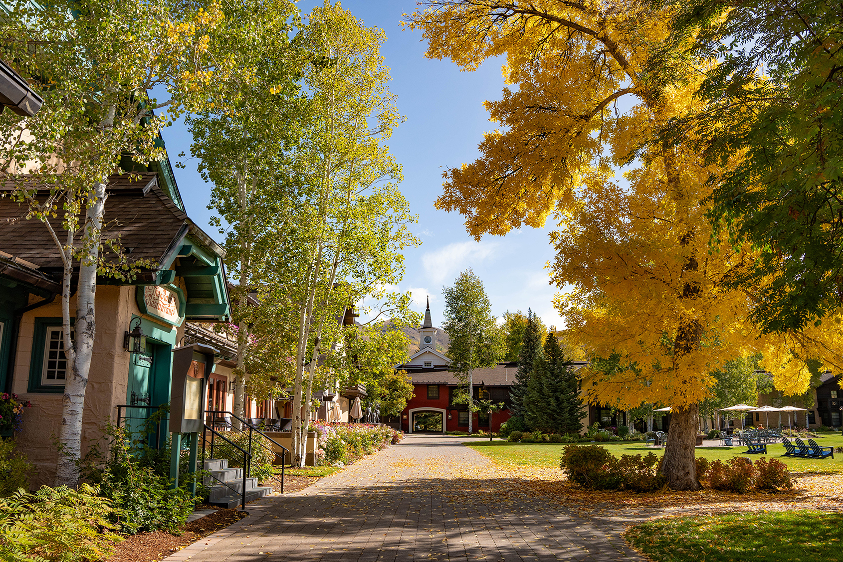 A picturesque courtyard at Sun Valley Lodge with vibrant autumn foliage, charming buildings, and a clear blue sky