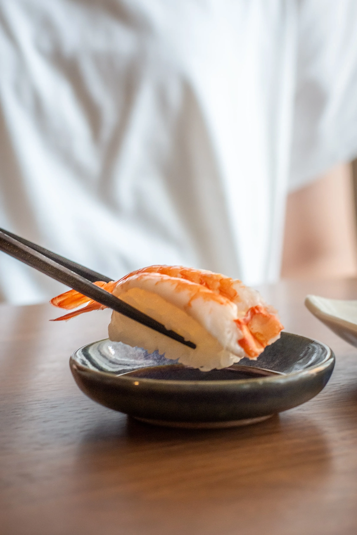 A piece of seafood sushi being held in chopsticks