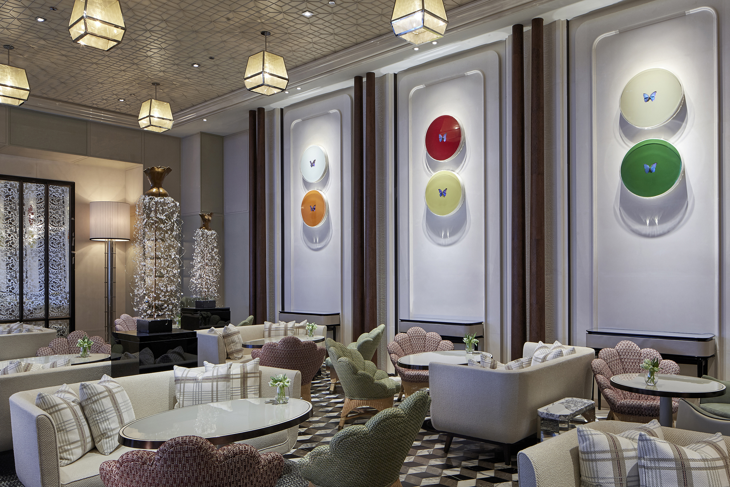 The high-ceilinged Butterfly Room at Rosewood Hong Kong featuring cream and pastel coloured furniture, butterfly decorated circle wall decor and patterned ceiling