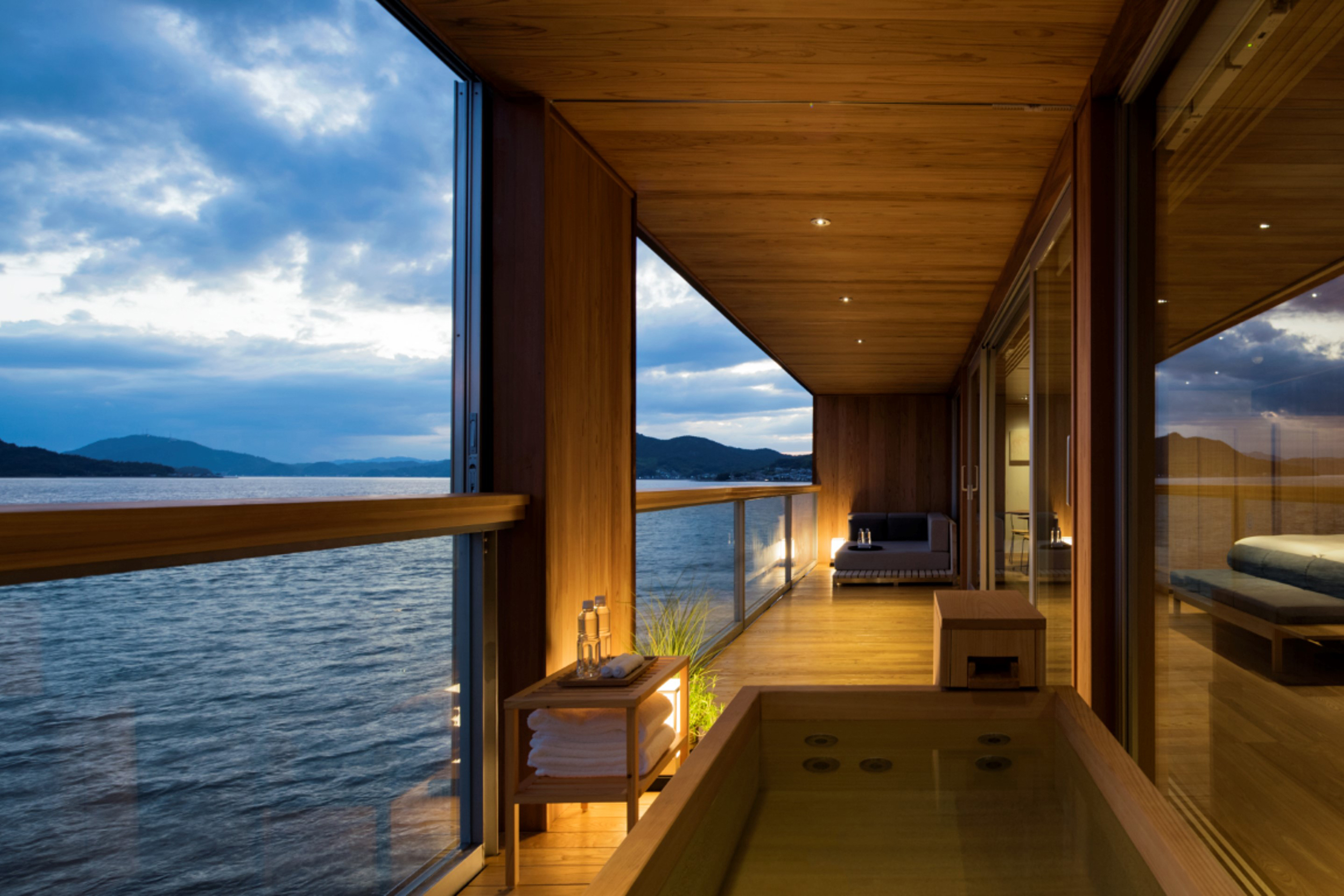 The terrace of a suite aboard Guntu lit up at night, featuirng a bath area and comfy seating