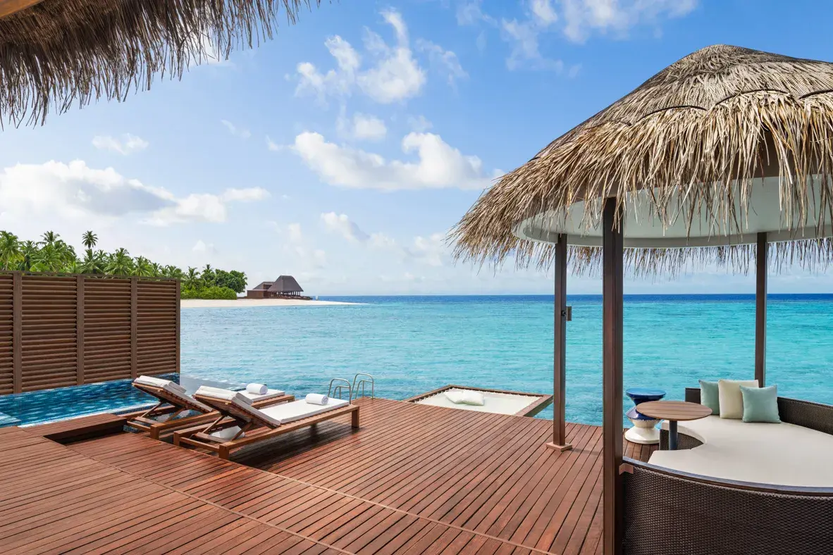 Private outdoor deck of a Superior Overwater One-Bedroom Villa at W Maldives featuring sun loungers, a plunge pool, a shaded daybed pavilion, and direct access to the crystal-clear turquoise waters of the Indian Ocean.