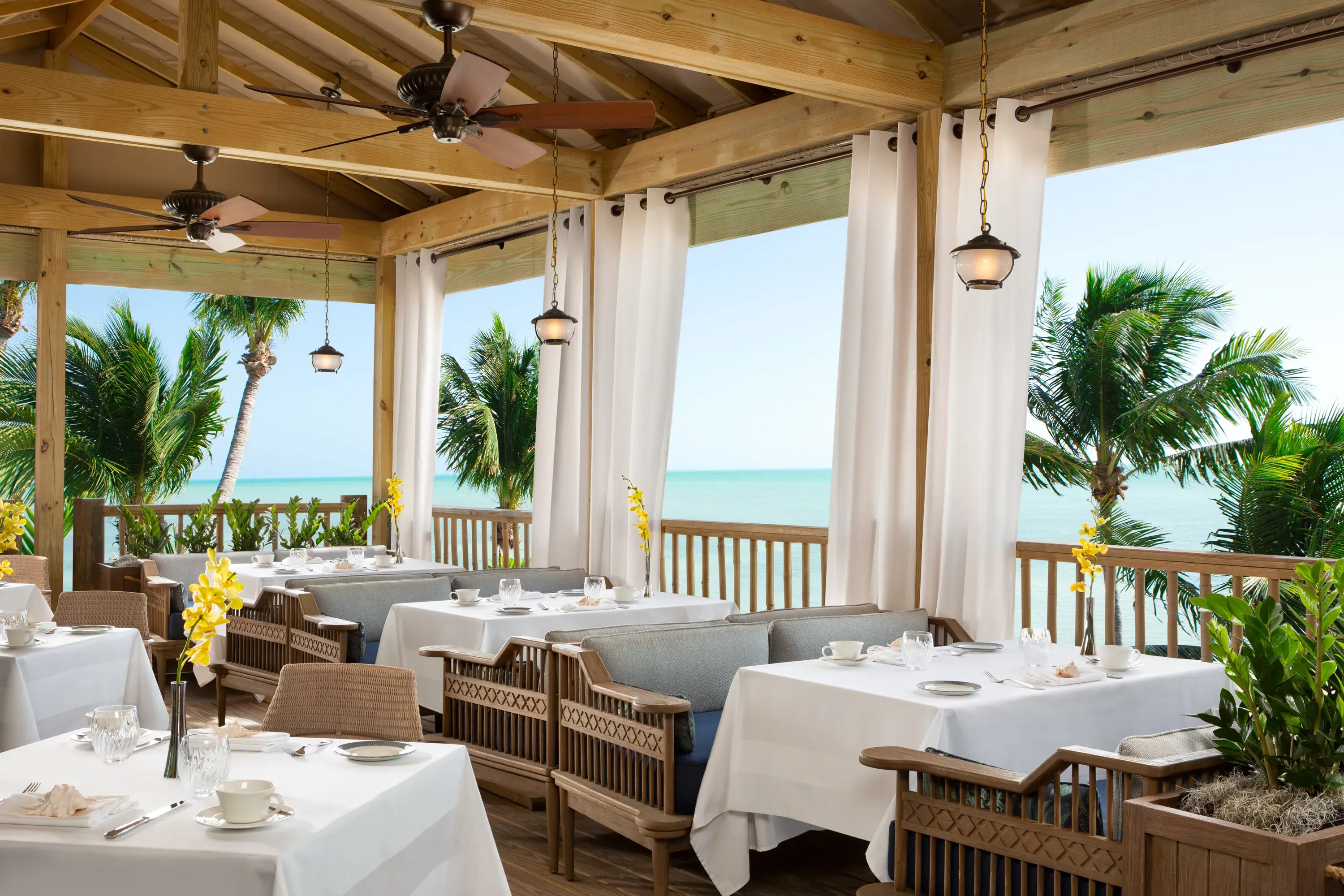 Oceanfront dining terrace at Little Palm Island Resort in Florida with white tablecloths, tropical palm views, and elegant coastal decor.