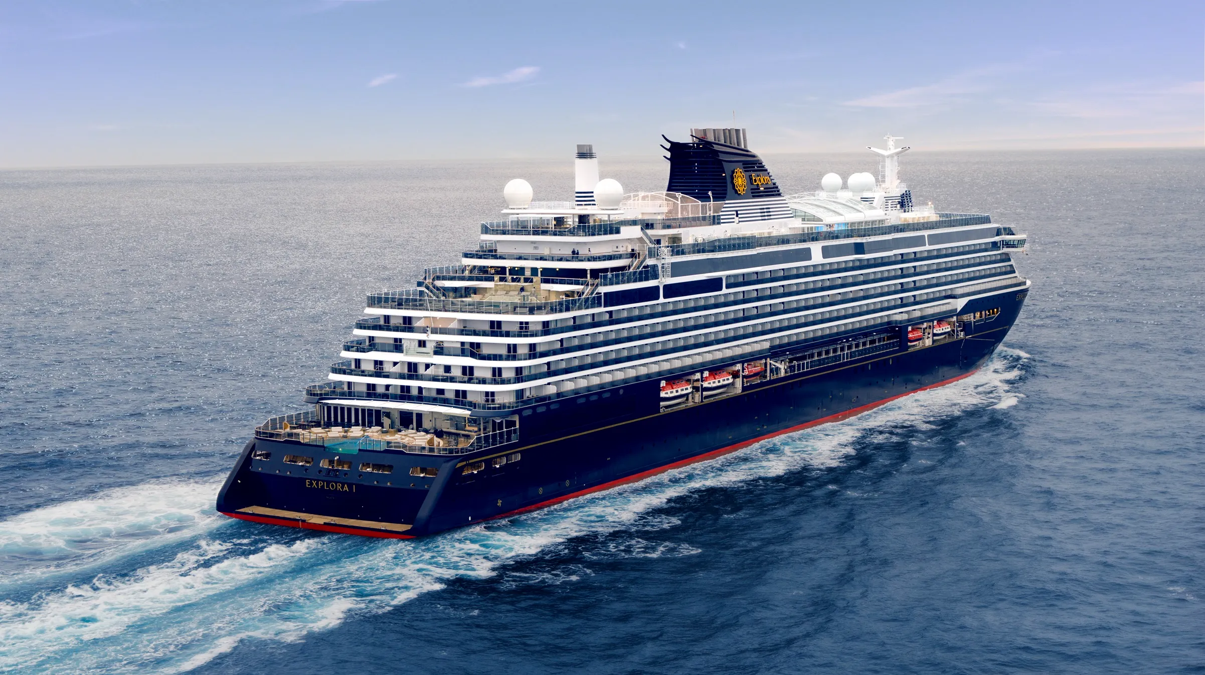 Explora I cruise ship gliding across calm ocean waters beneath a clear blue sky.