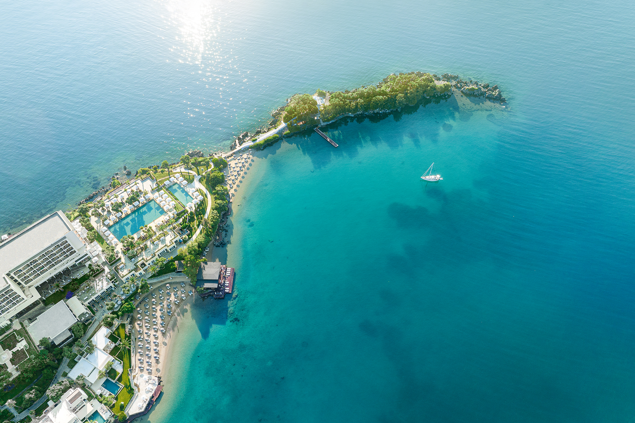 Aerial view of Grecotel Corfu Imperial resort with beachfront, luxury hotel, and turquoise Ionian Sea.