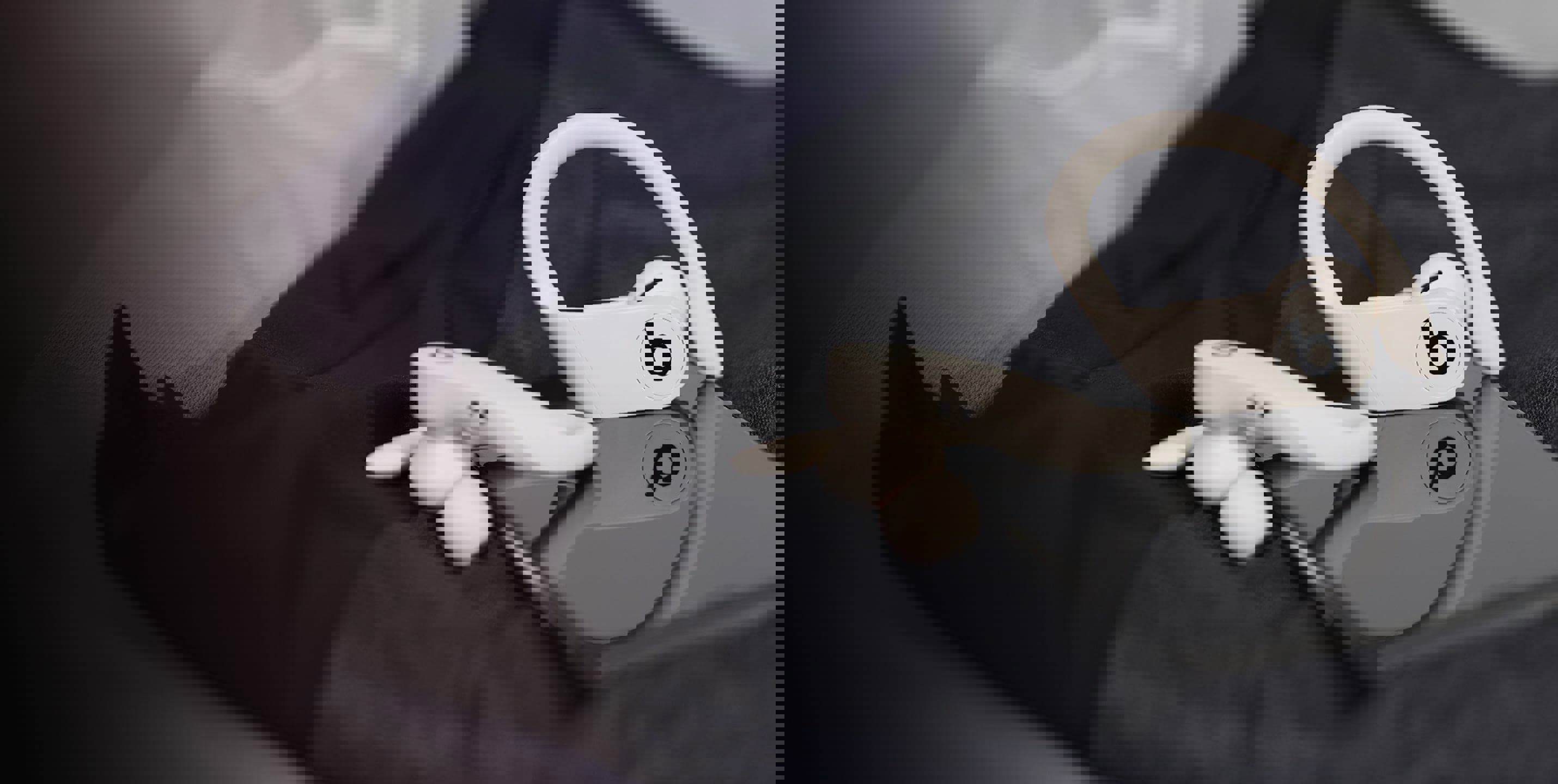 A pair of the Beats by Dre 'Powerbeats Pro' model wireless earphones sit on top of a mobile phone