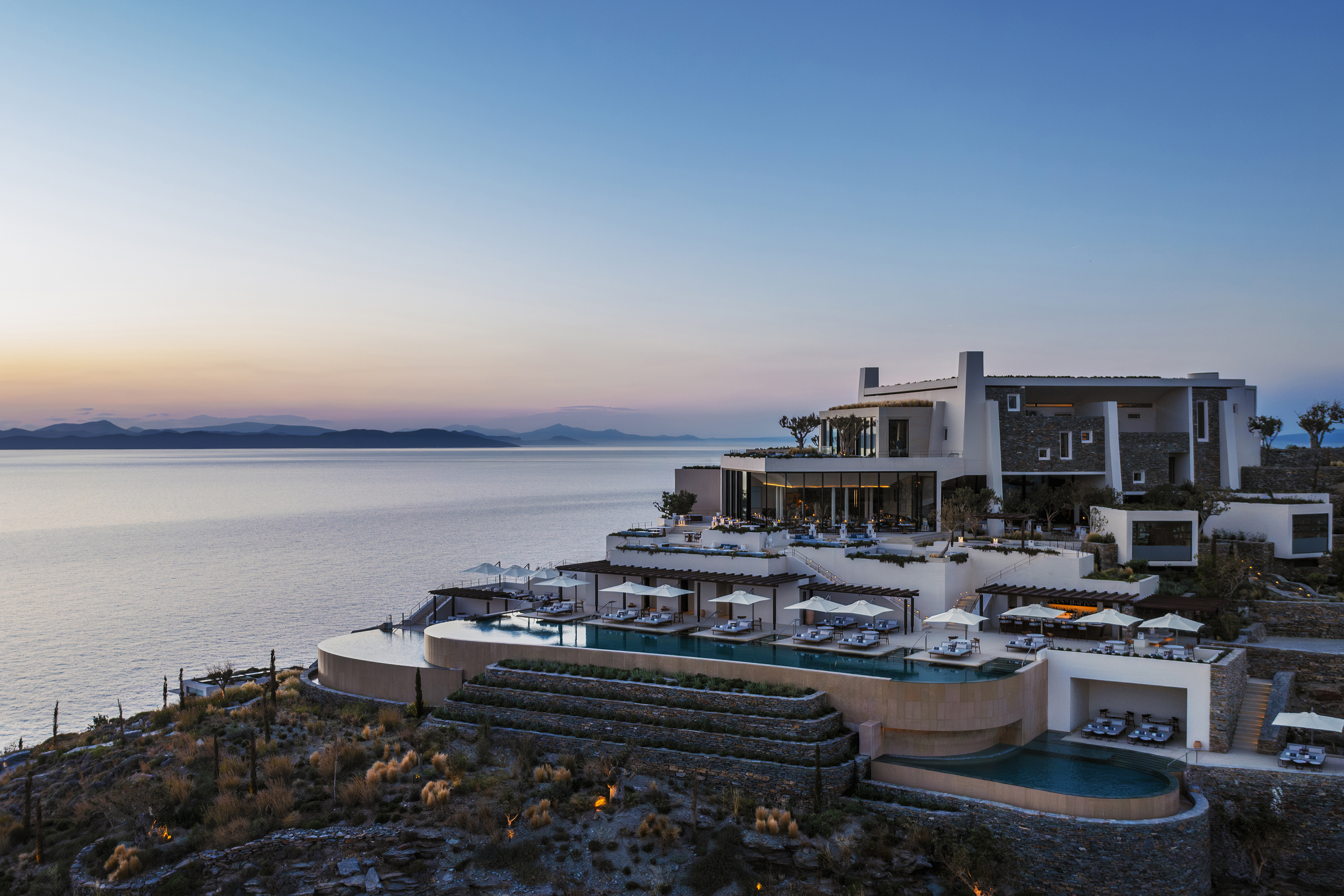 View of hotel exterior showing a tiered design from restaurant to pool at sunset