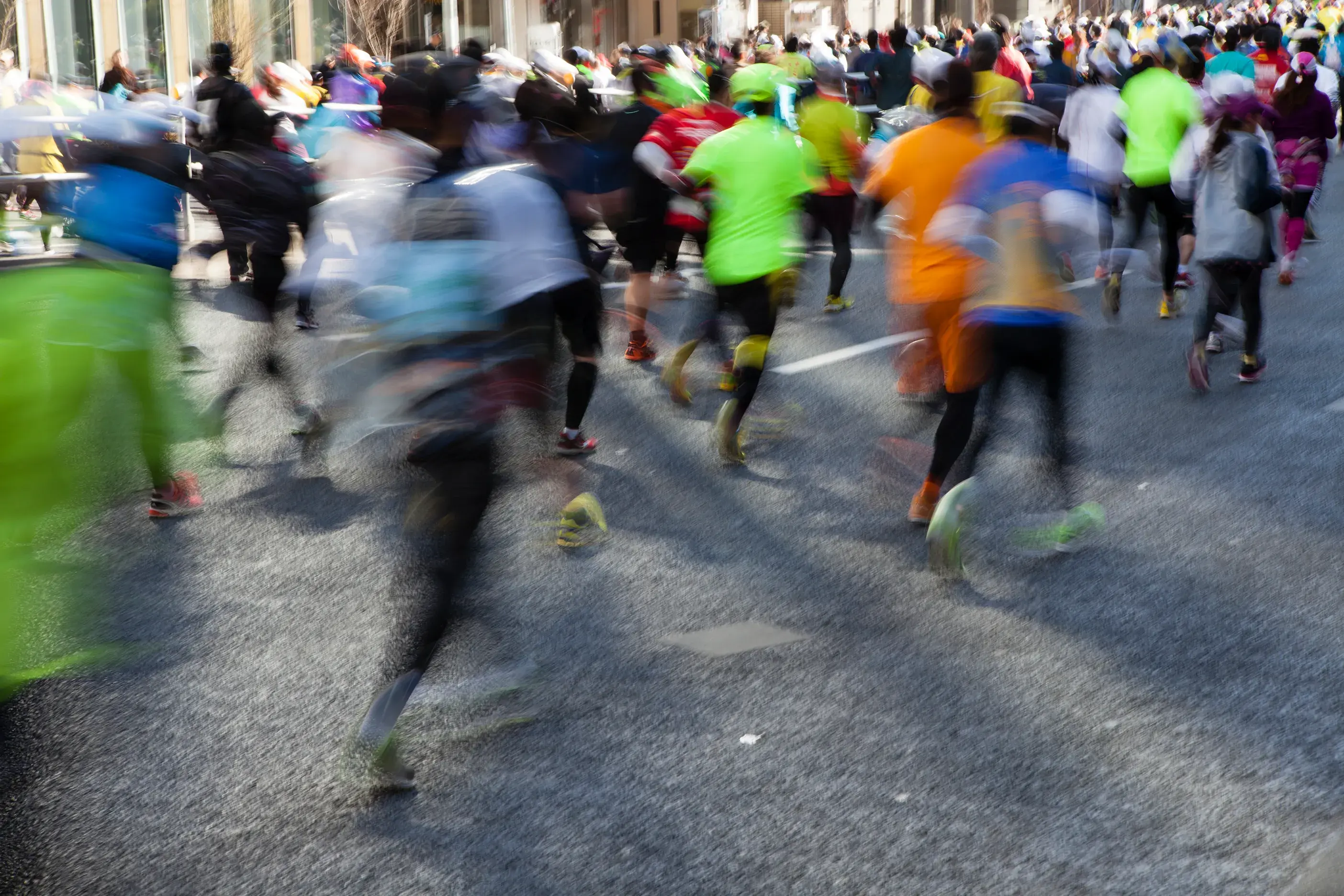 Group of runners at the Tokyo Marathon in colourful athletic gear participating in a city marathon on a sunny day.