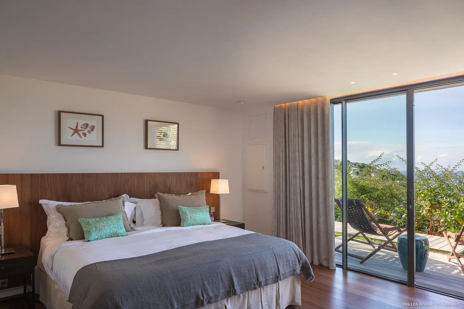 Bright contemporary bedroom at Les Roches Villa in St Barths with large glass doors opening to a private terrace and lush tropical views.