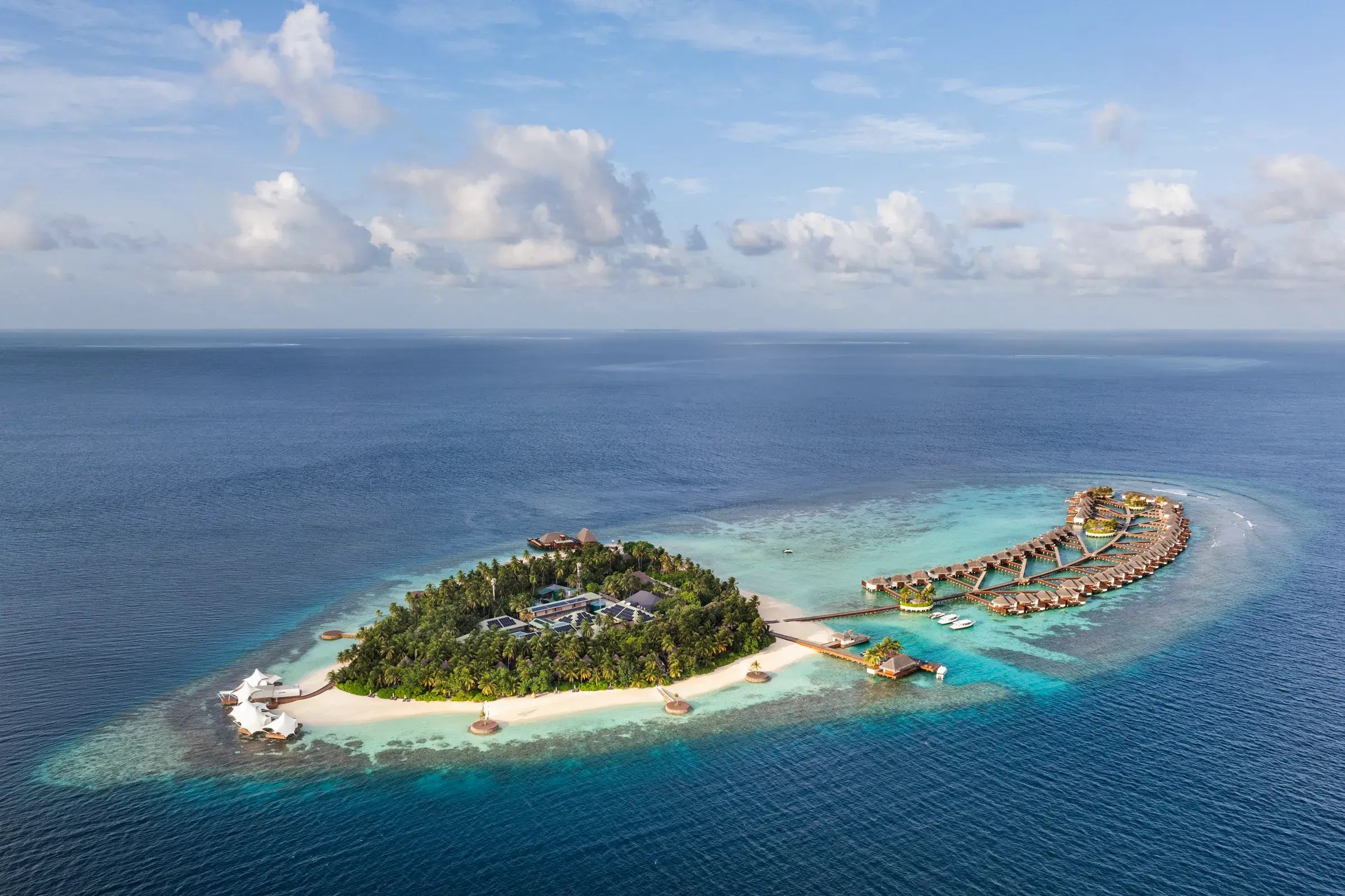 Aerial view of W Maldives private island resort featuring white-sand beaches, turquoise lagoons, lush tropical landscapes, and luxury overwater villas surrounded by the crystal-clear Indian Ocean