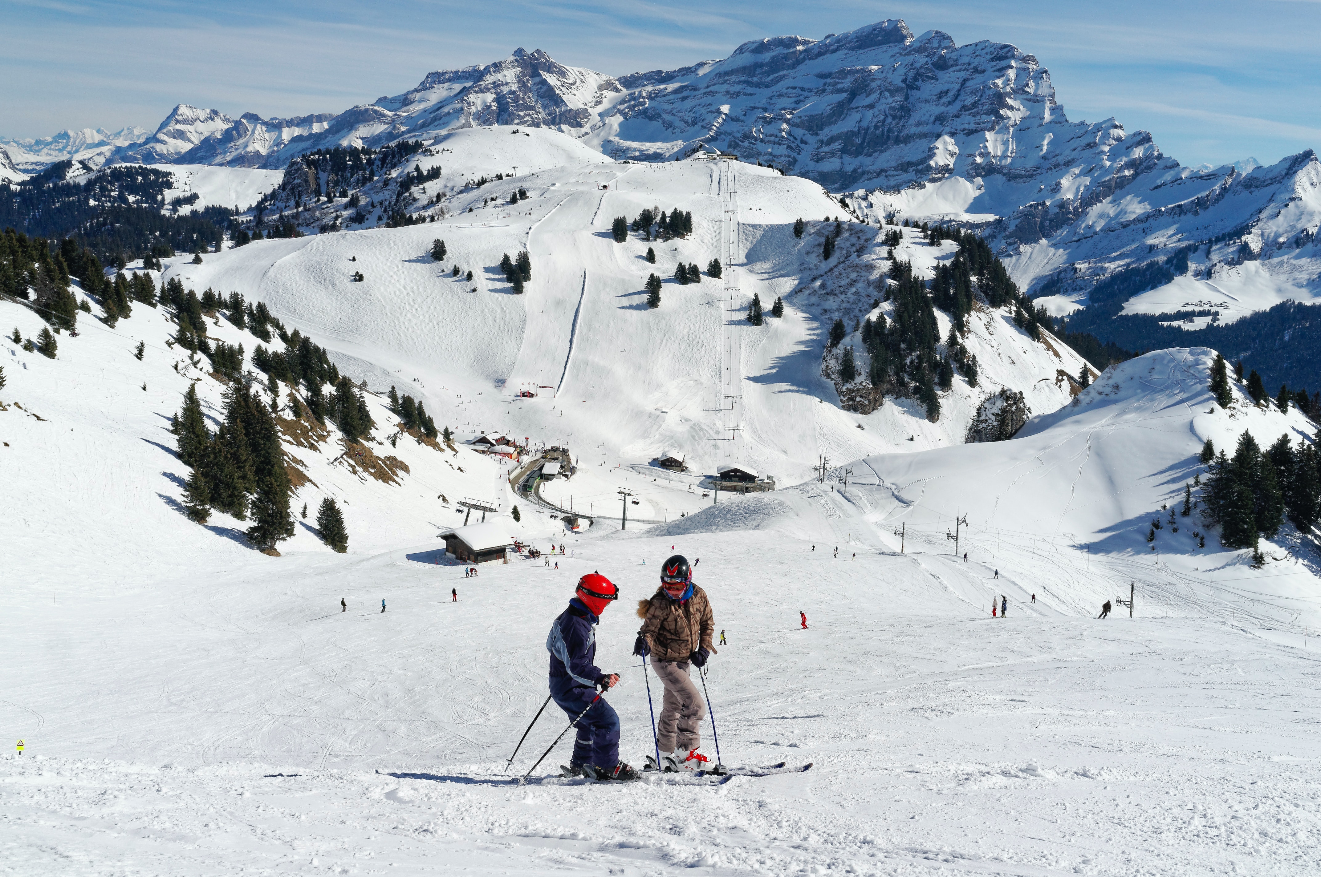 Two skiers stopped to chat at the top of a ski slope