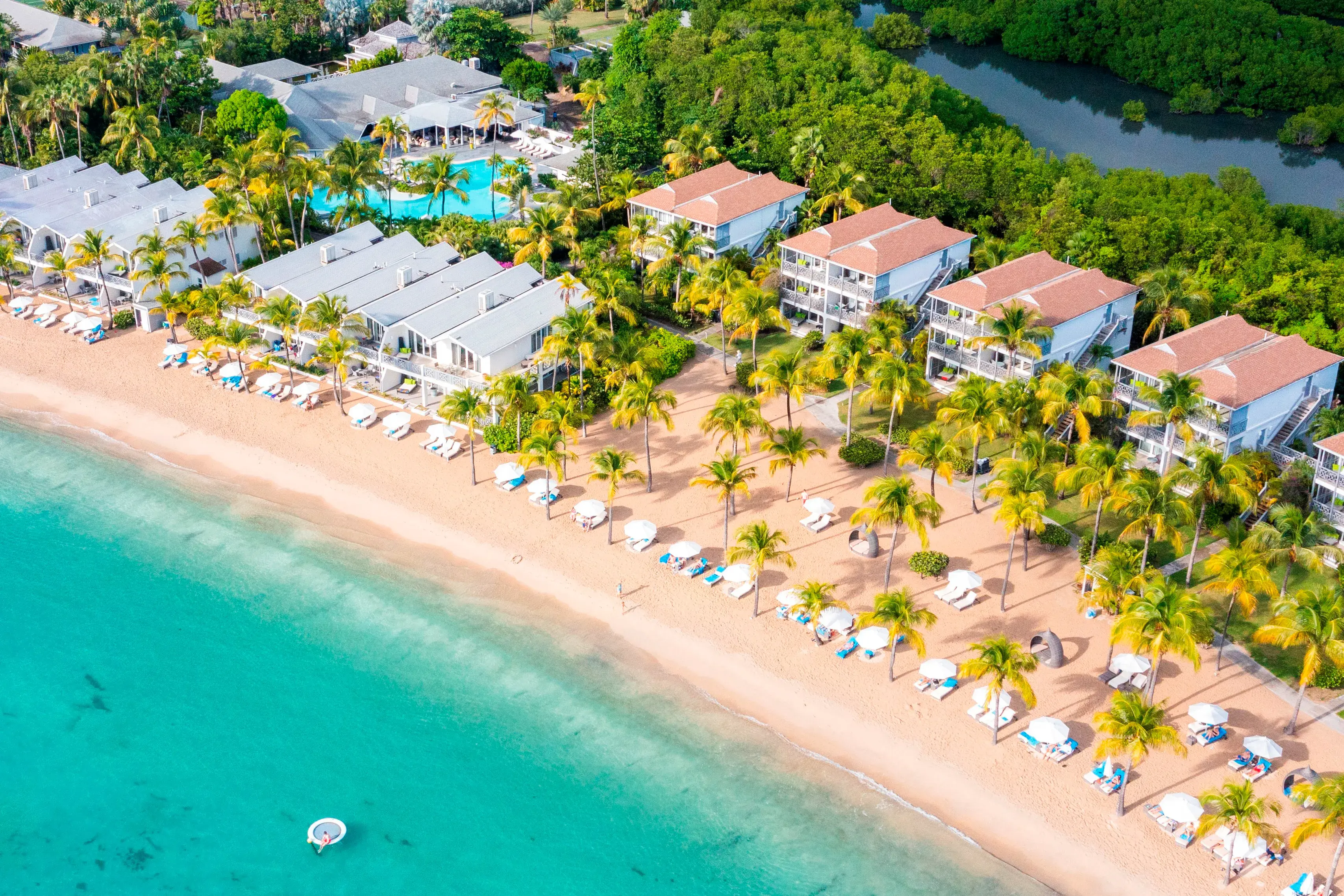 Sun loungers, palms and buildings of Carlisle Bay lining the beach