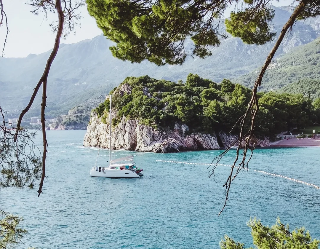 A private yacht charter sailing between rocky green shores on the Mediterranean