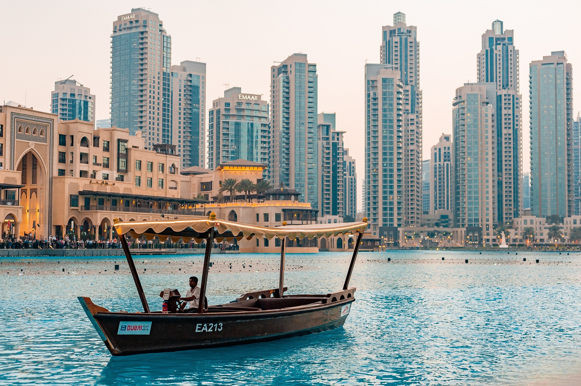 A view of a boat sailing on the marina in Downtown Dubai with both sandstone buildings and glass skyscrapers seen in the background