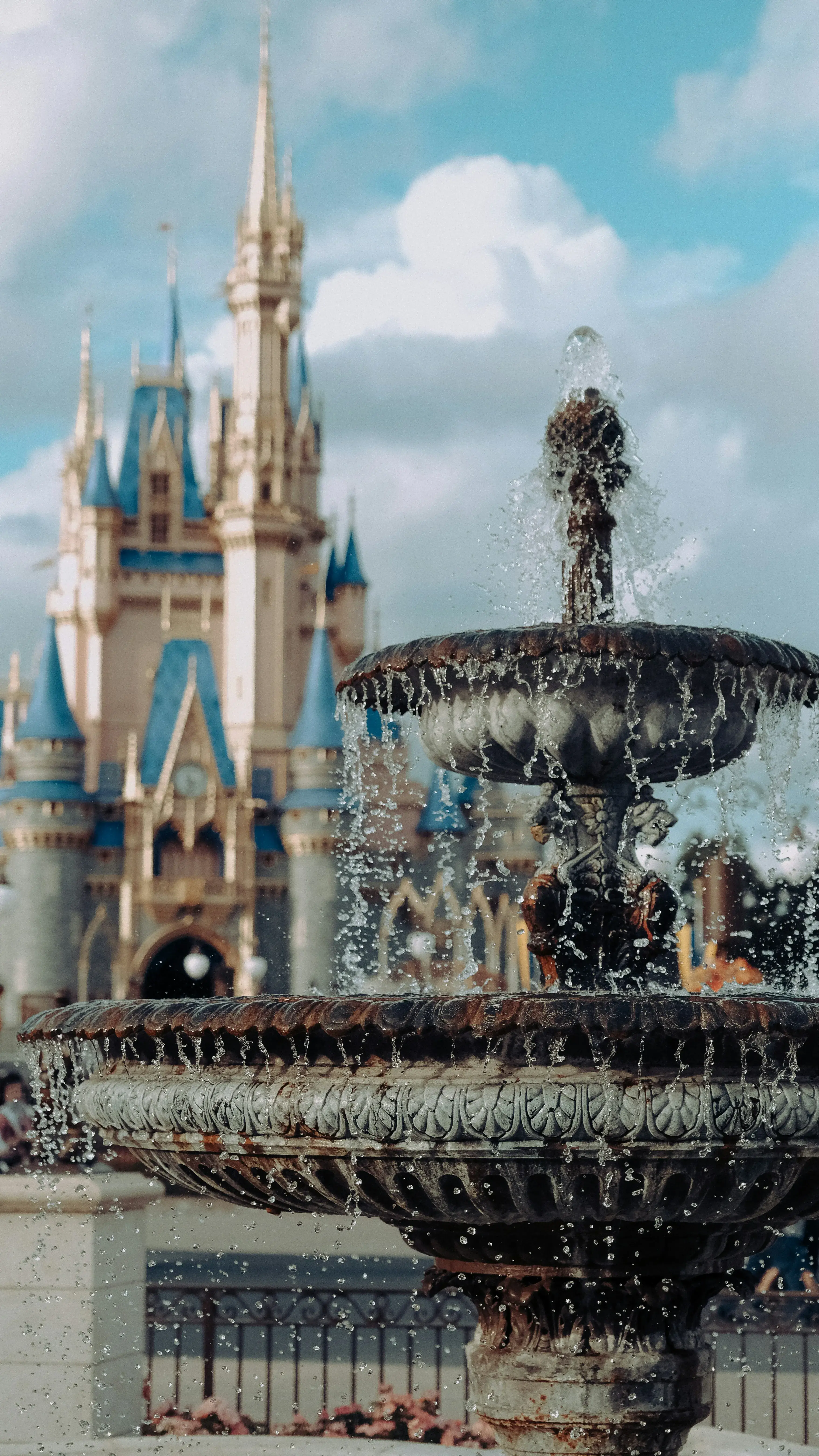Decorative water fountain in the foreground with Cinderella's castle in soft focus behind it ay Walt Disney World Orlando.
