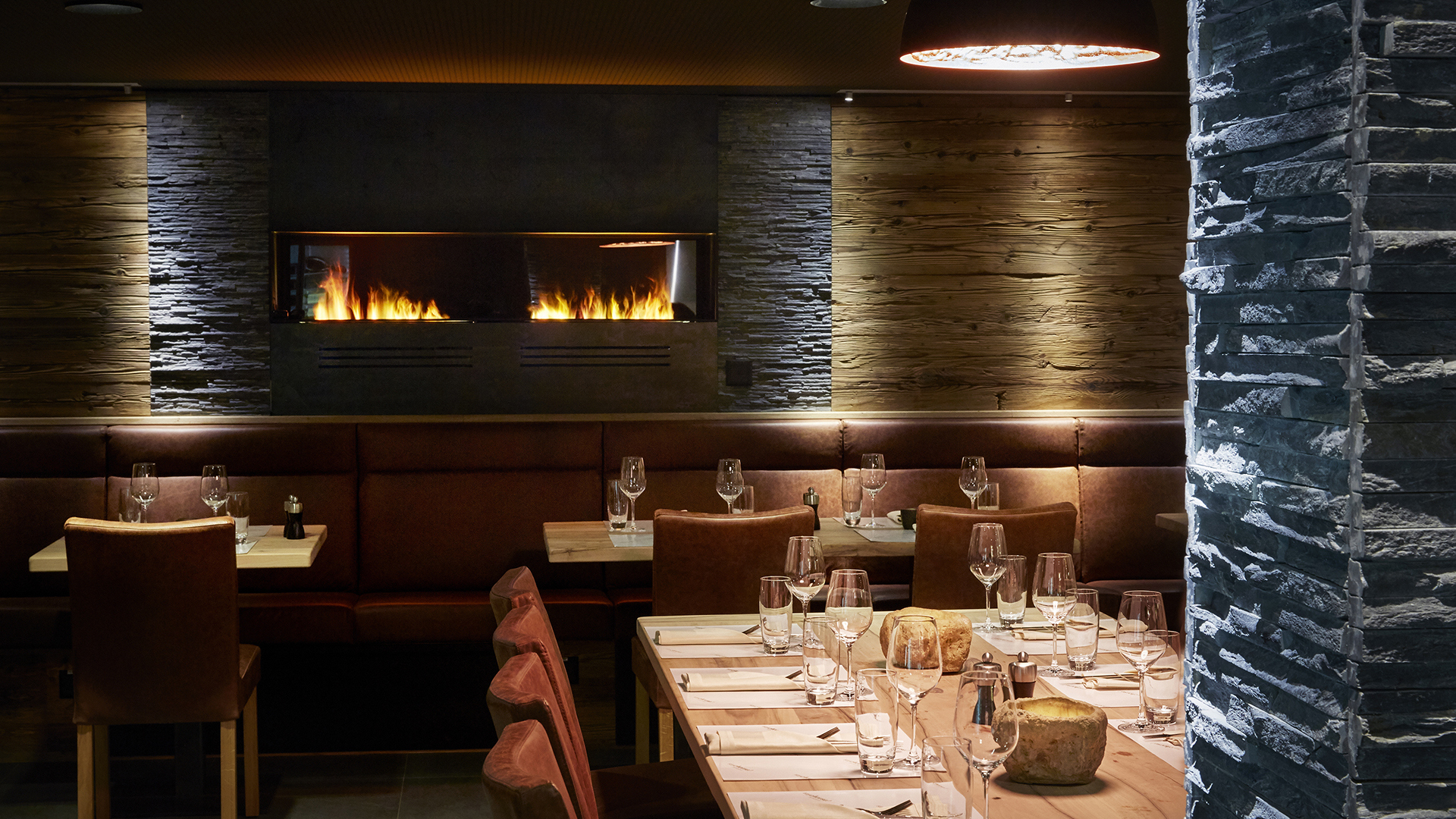 A cosy restaurant with tables set for dinner and a lit fireplace