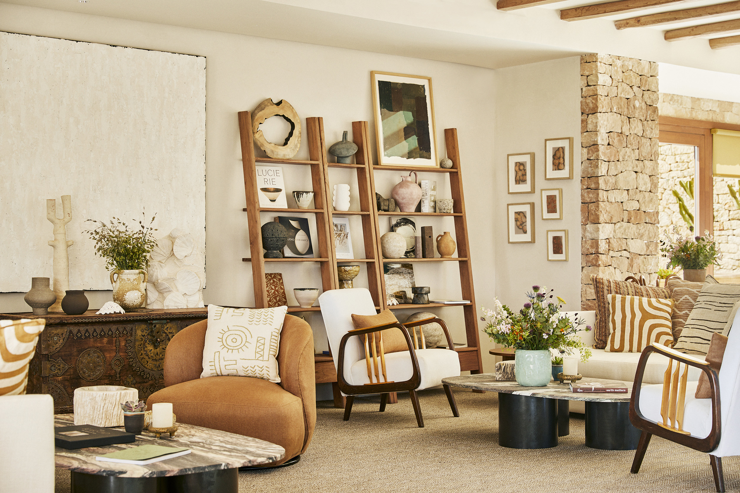 A cosy lobby area at Teranka with furniture decorated in patterned cushions and two shelves decorated with vases and pictures 