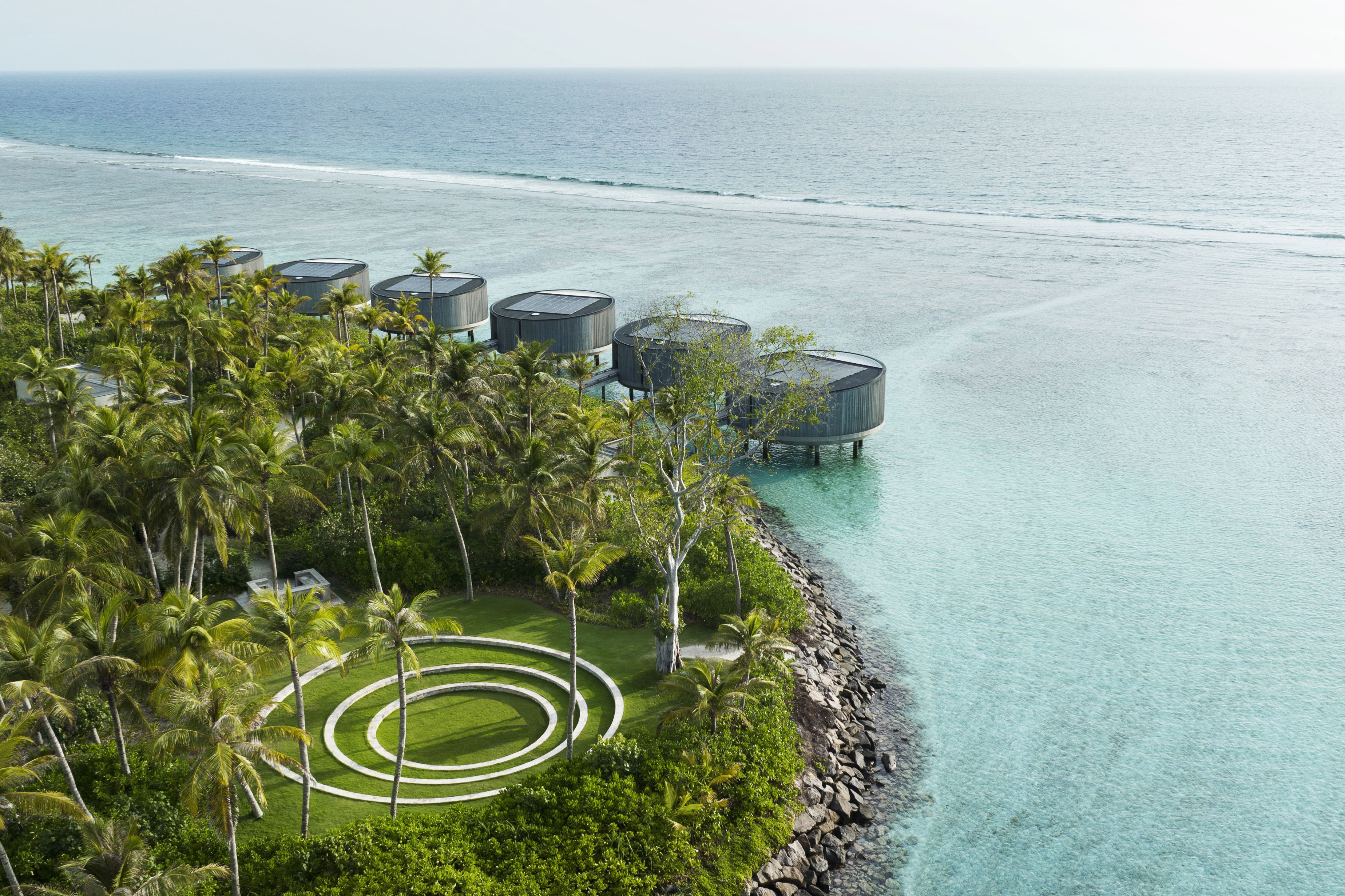 Lush green yoga garden with circle stone feature and hotel rooms facing the ocean