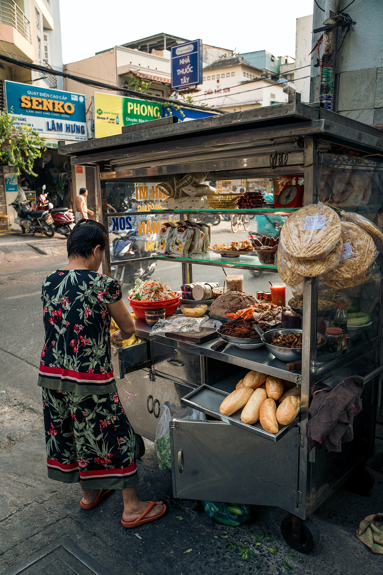 A woman preparing food at a food cart that is full of different foods