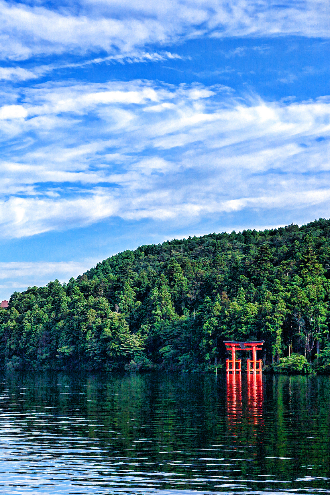 A view of the Hakone-jinja shrine in front of lush greenery across the lake
