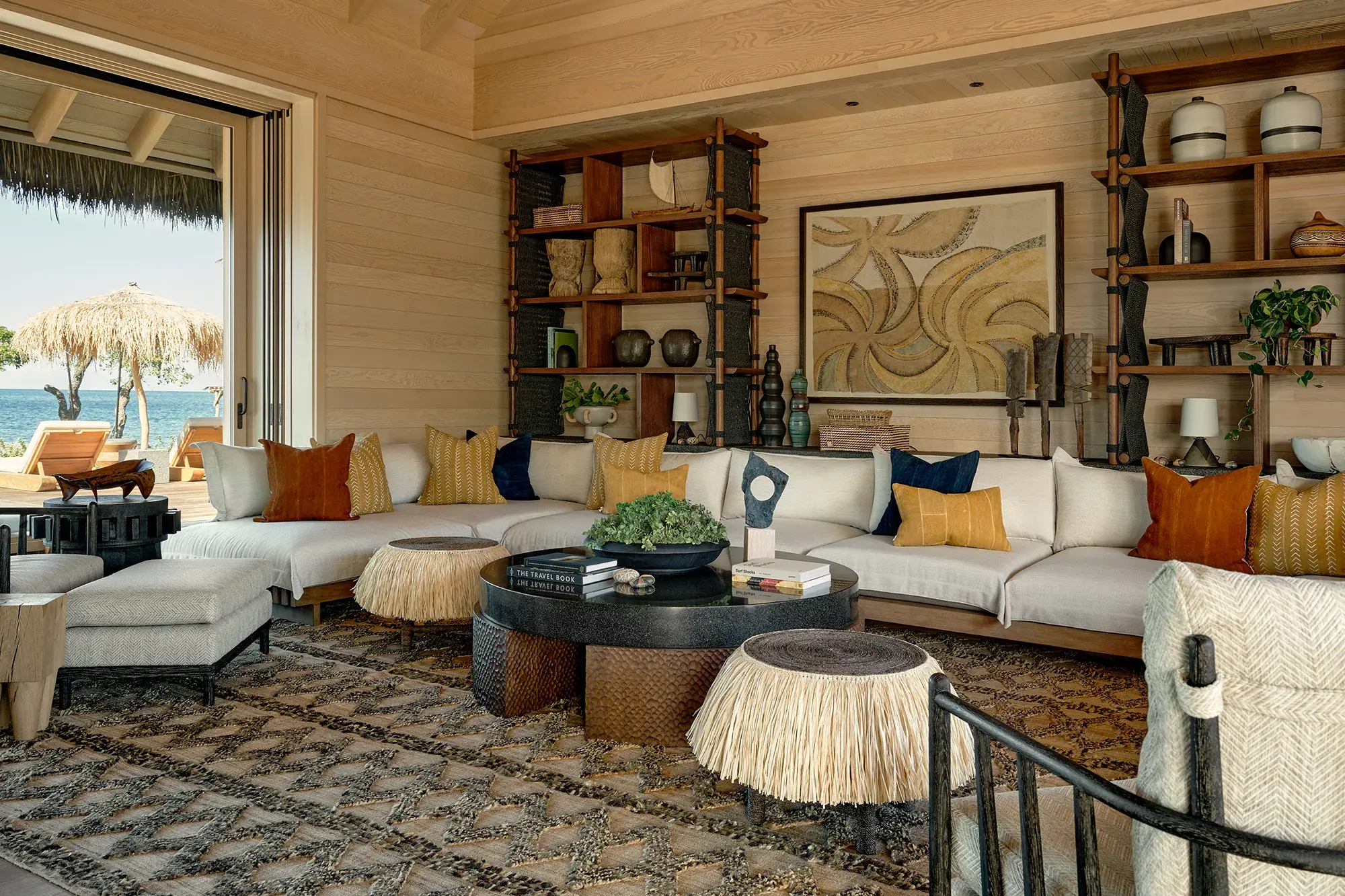 The living room of a Signature Suite Maheawalu at Rosewood Kona Village with eclectic decor, long comfy sofas and shelves with trinkets and vases