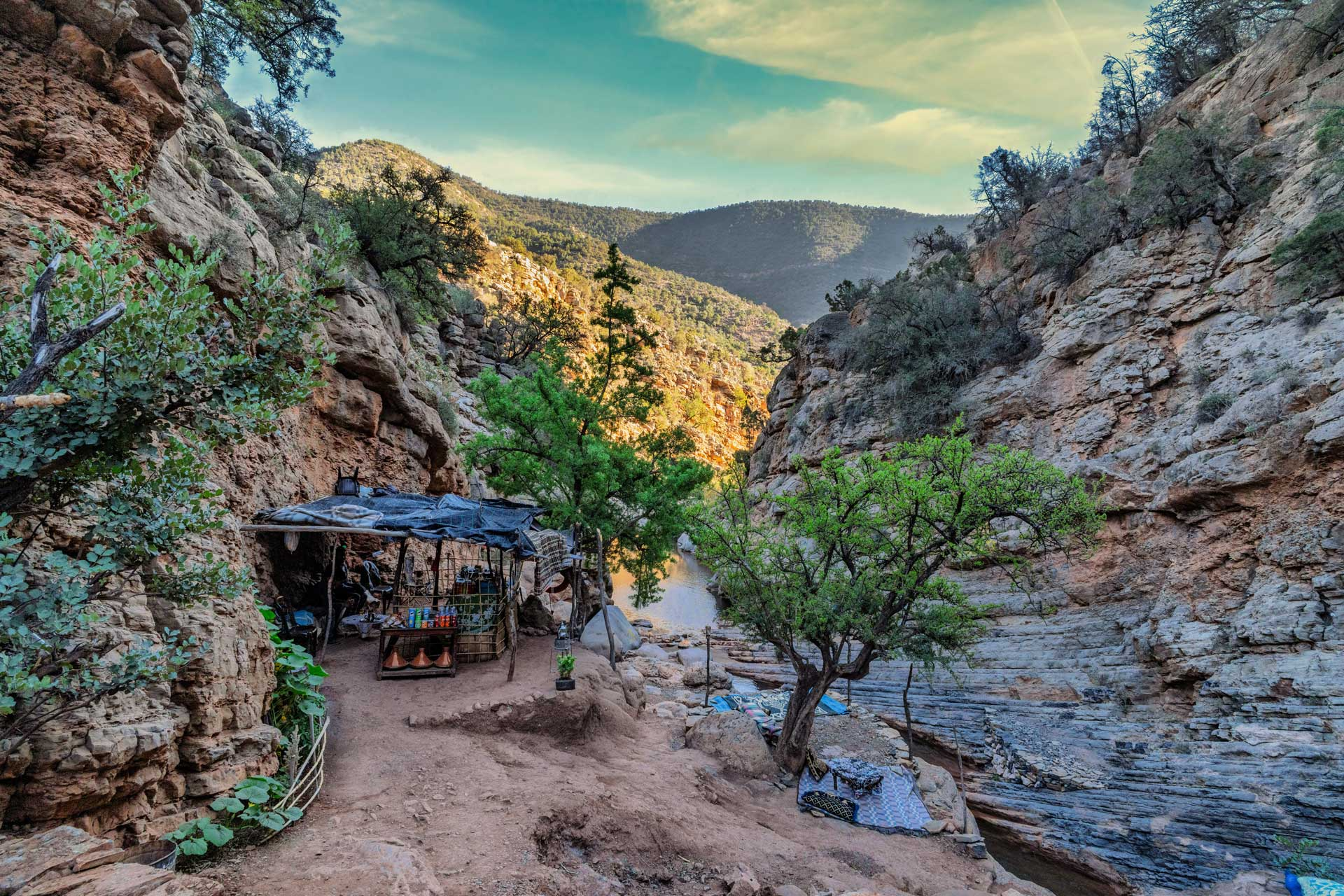 Scenic mountain valley near Royal Mansour Tamuda Bay with rocky cliffs, greenery, and a riverside shelter.