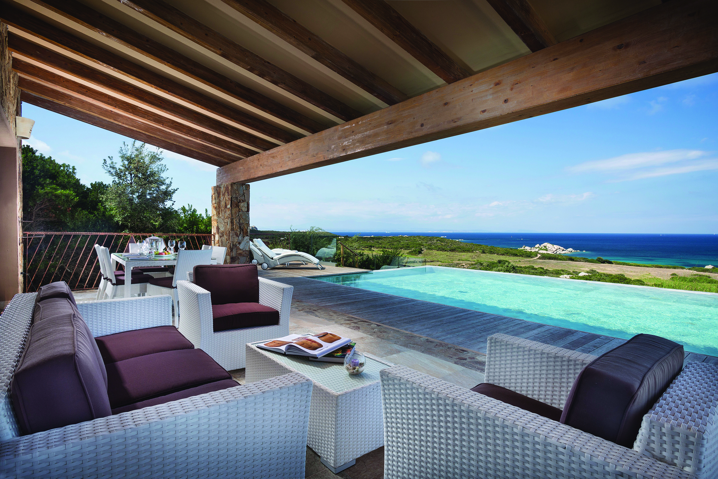 A large suite terrace featuring white rattan furniture and a private infinity pool overlooking the ocean