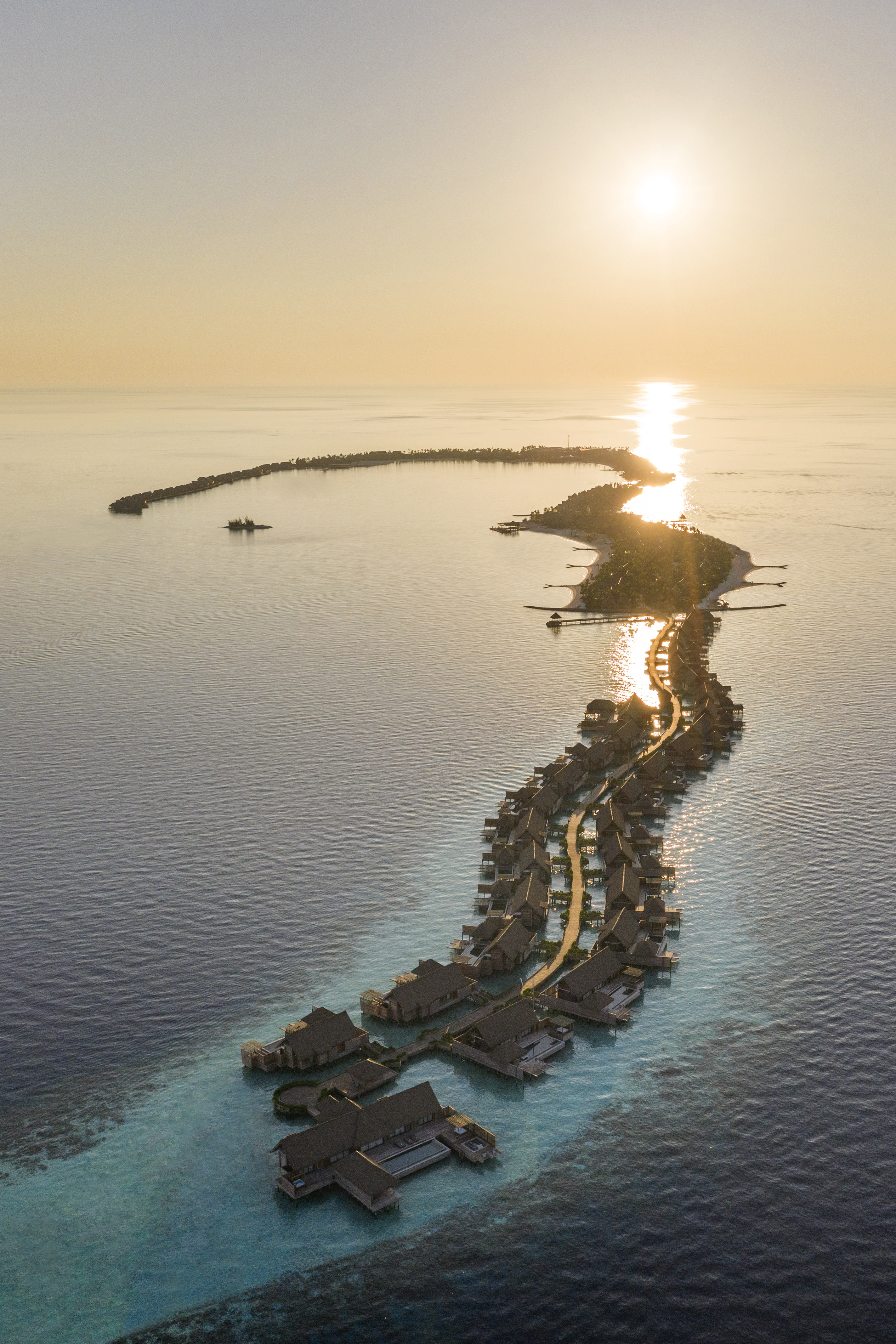 Birds eye view of Ithaafushi main island showing overwater villas and curve of lagoon bay