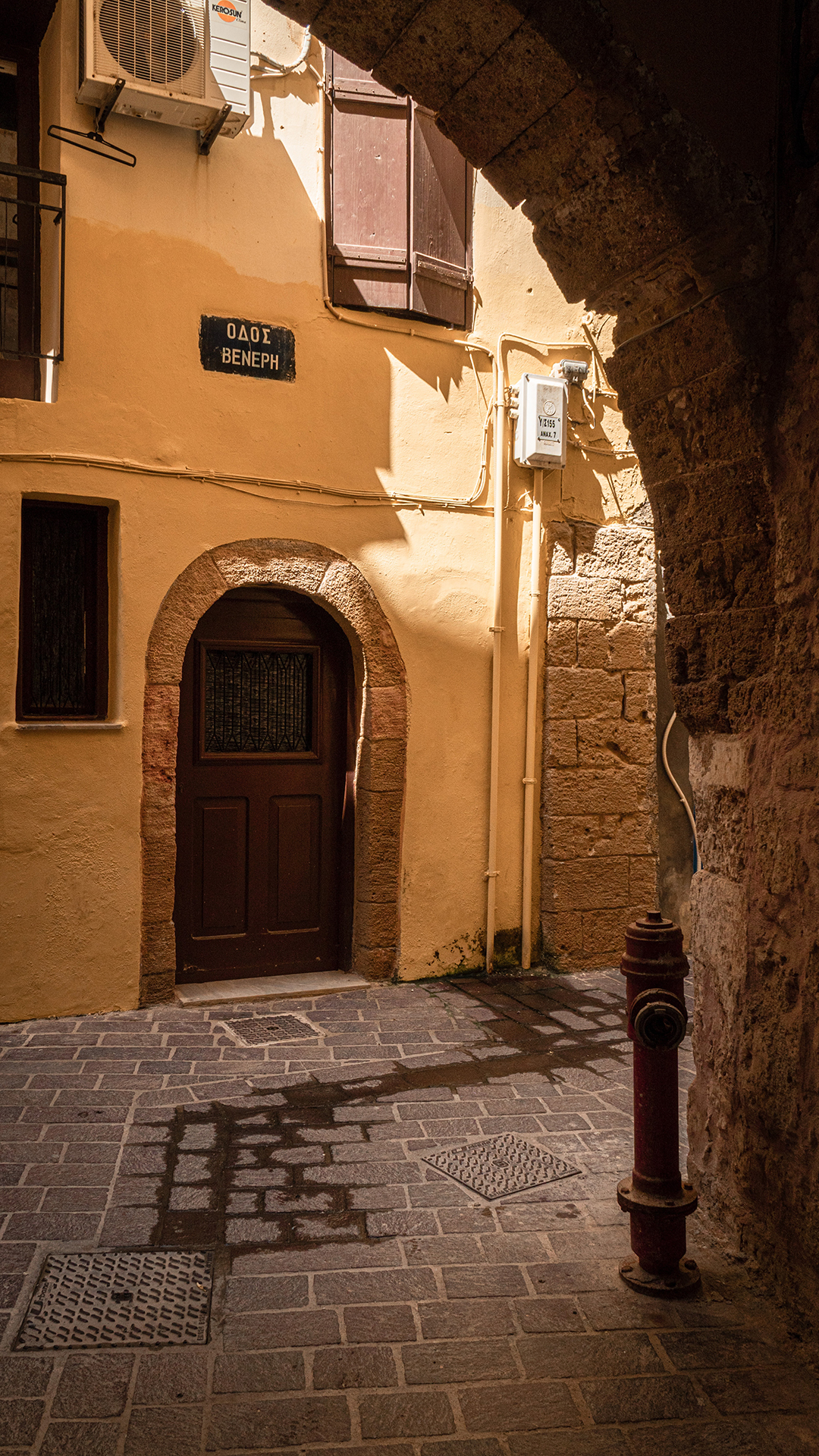 Brown wooden door on brown concrete building in small Greek street