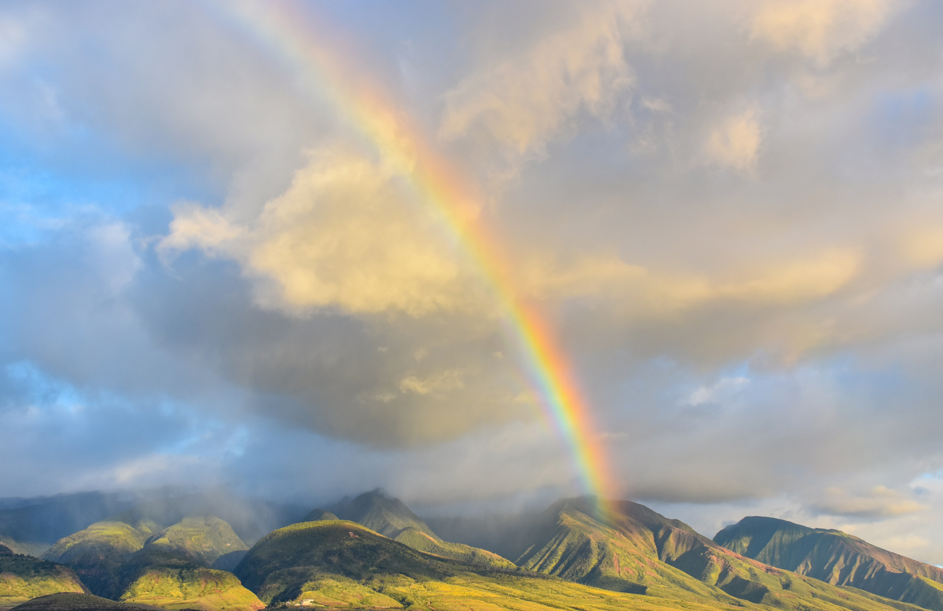 A rainbow shining over green mountains in Maui, Hawaii