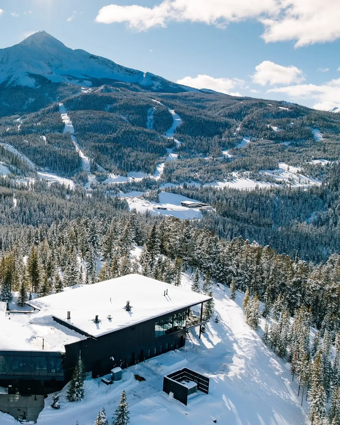 Sky Lodge and surrounding snowy landscape of fir trees at One&Only Moonlight Basin, Montana, USA