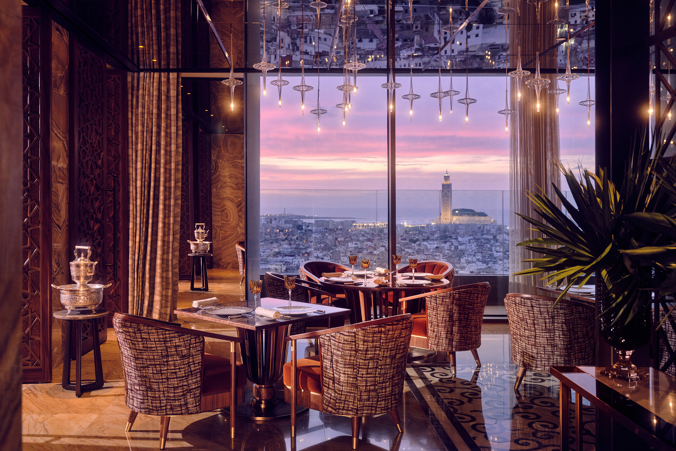 The interior of La Grande Table Marocaine at Royal Mansour Casablanca lit up at night with a view of the city at sunset