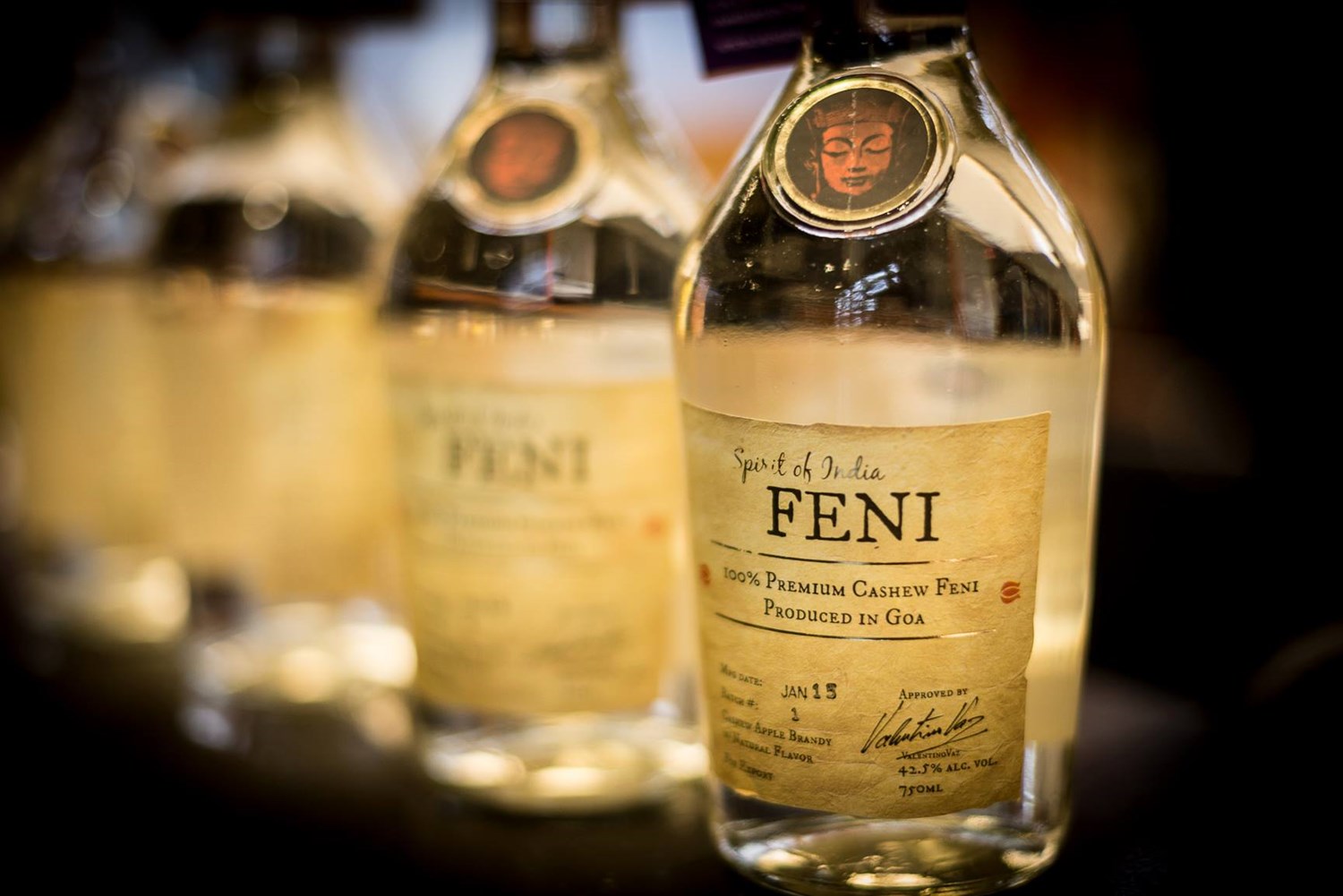 A close up of glass bottles with brown labels with the words Spirit of India Feni