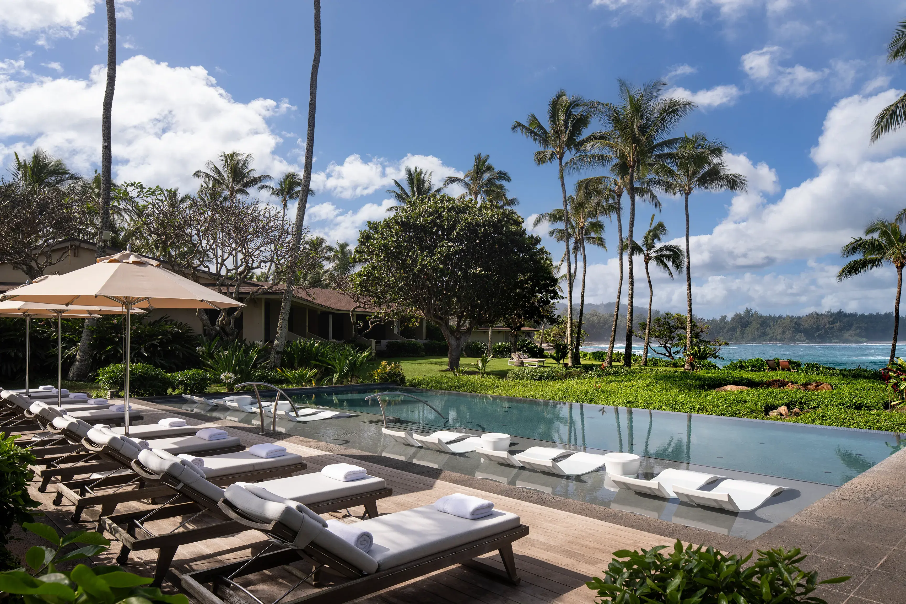 The Oceanfront Bungalow Pool at Ritz-Carlton Turtle Bay with sun loungers and umbrellas on one side and palm trees and the ocean on the other