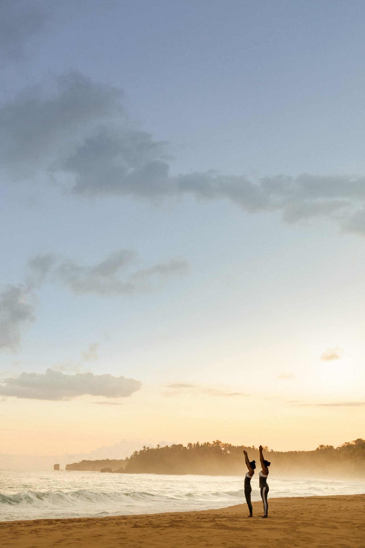 Two woman performing yoga on the beach