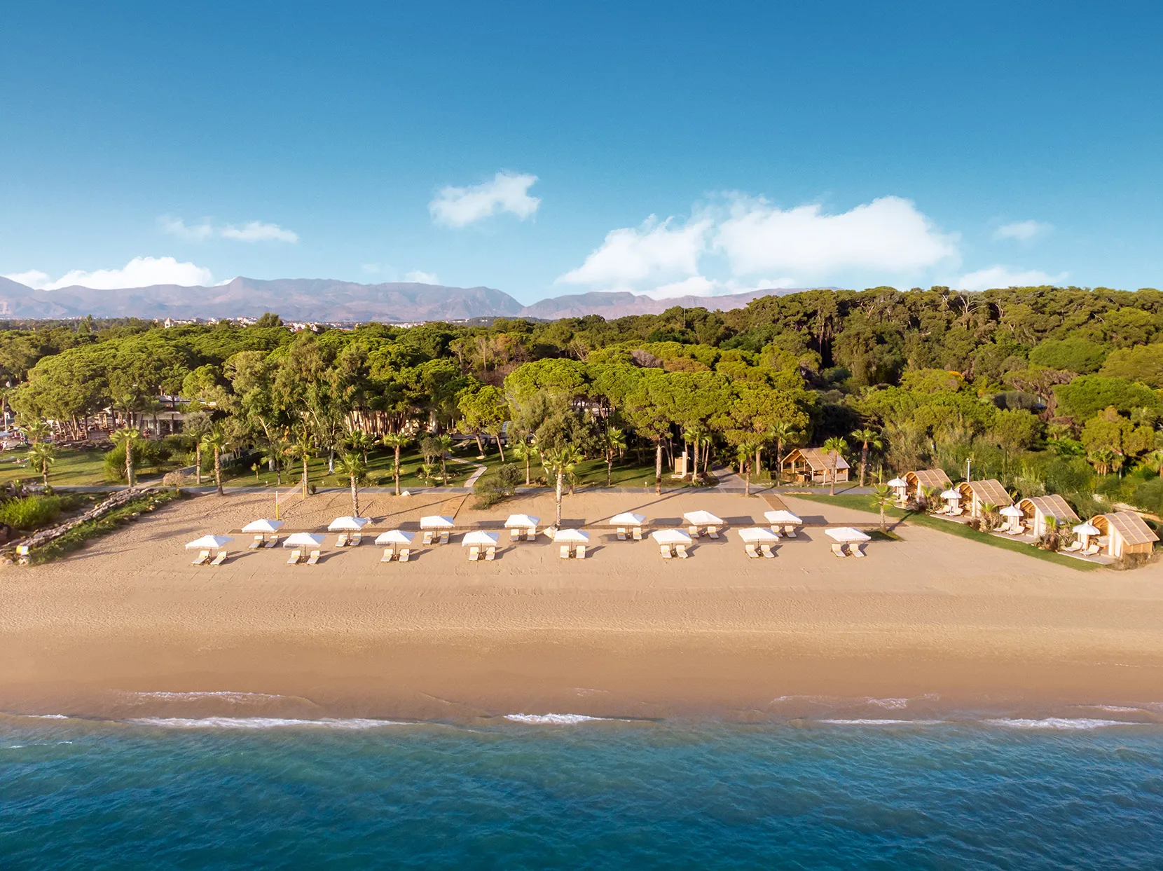 Europe, Turkey, Bijal, view of two rows of sunloungers on the beach facing the sea with a forest and mountains in the background