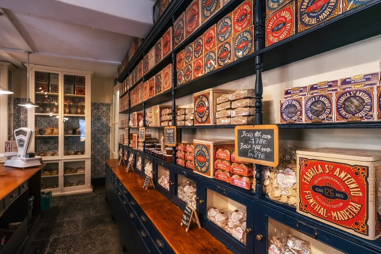 Traditional confectionery shop interior with shelves of packaged sweets, cakes, and decorative vintage tins.