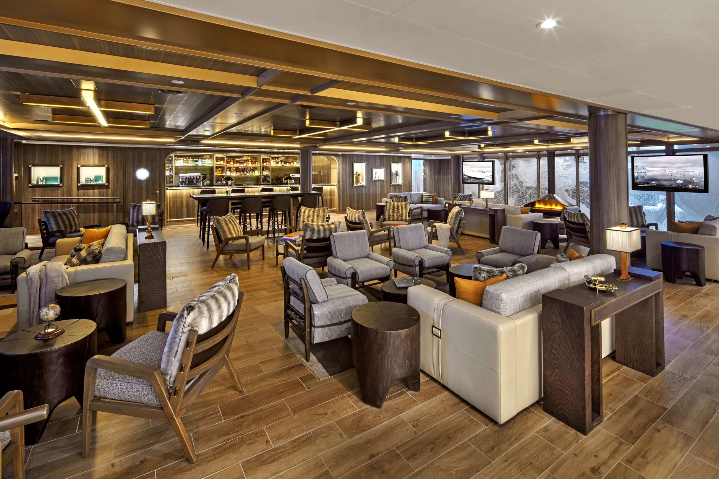 Modern lounge area with wooden flooring, comfortable seating, a bar, and large windows with scenic views.