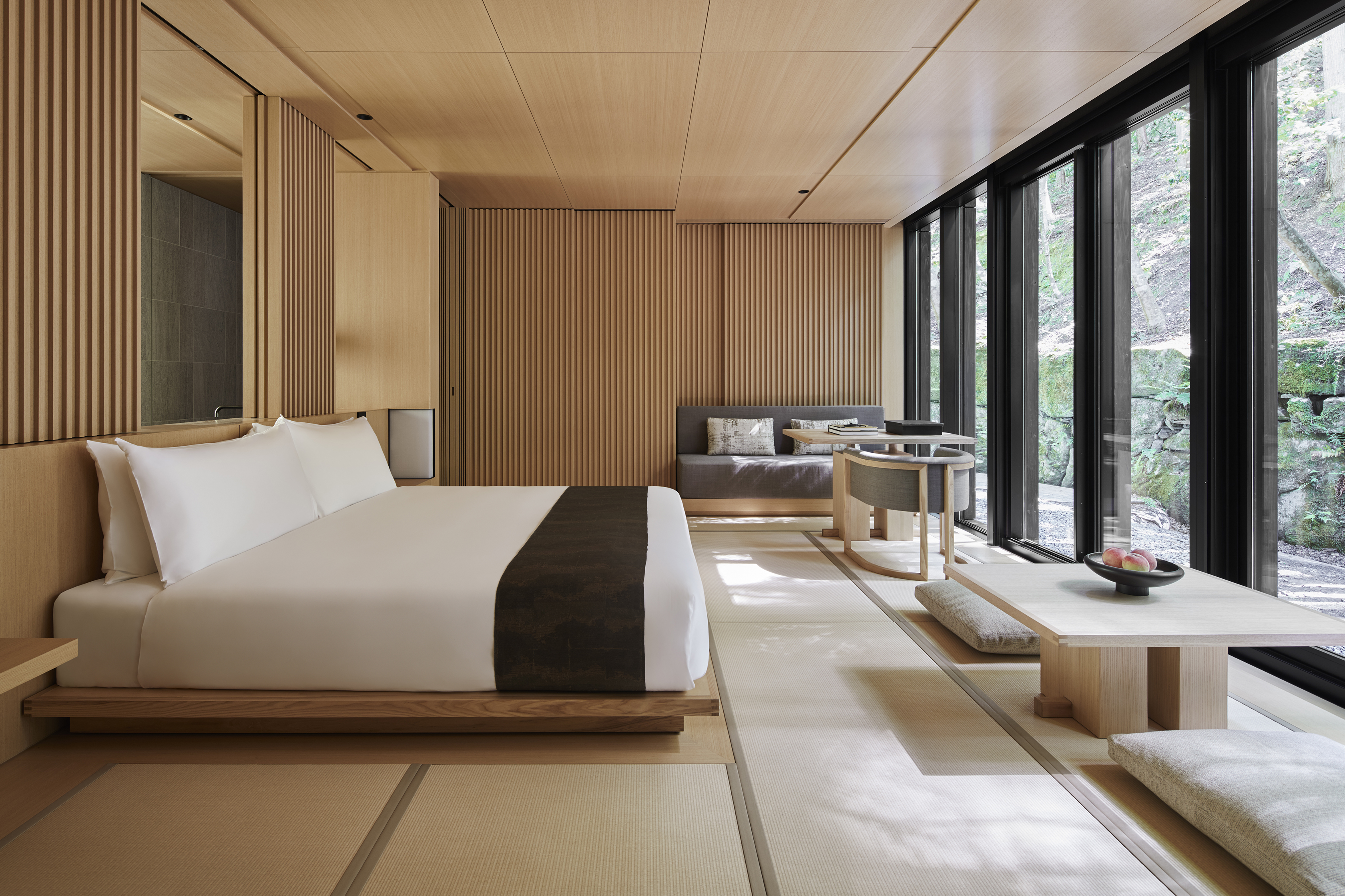 A large suite at Aman Kyoto featuring pale wood decor and a large bed facing large windows